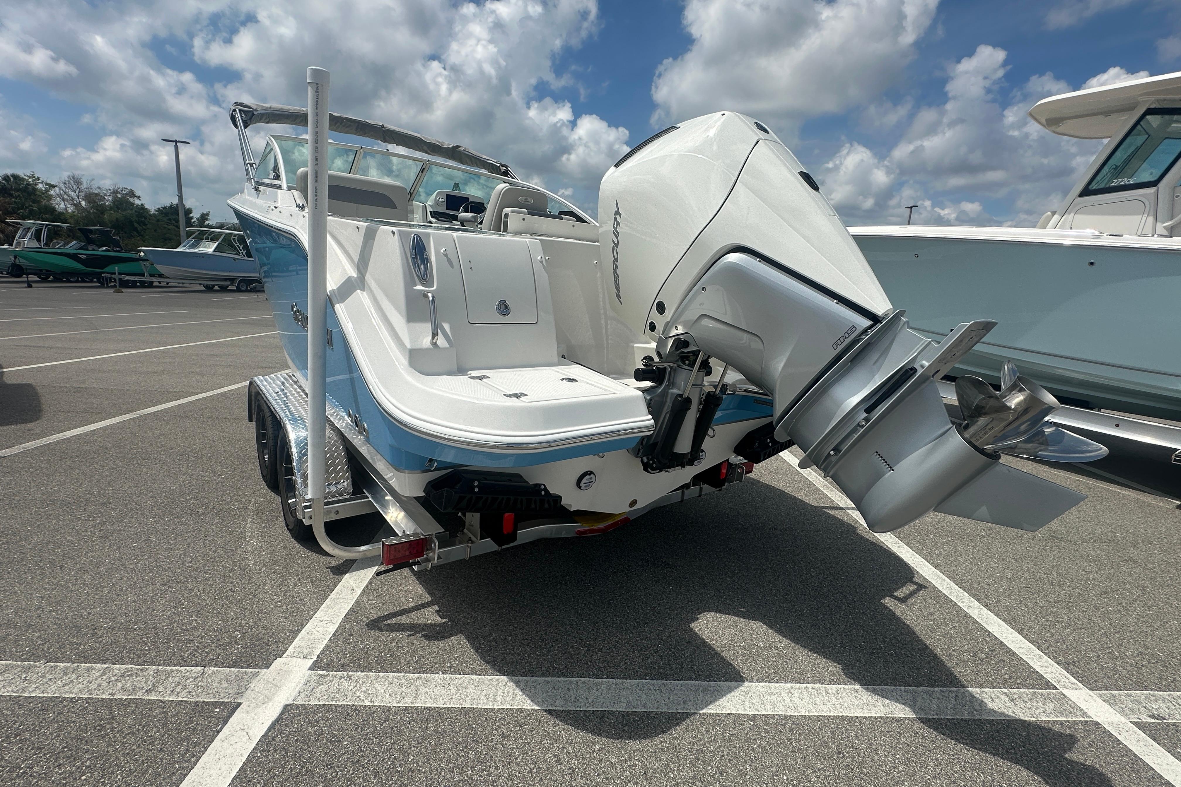 2026 Sailfish 226 DC boat on trailer, featuring powerful outboard motor, parked under cloudy sky.