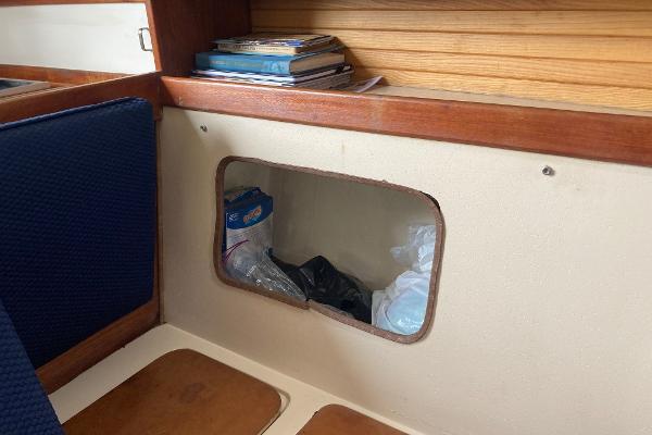 Interior of 1989 Catalina 30 sailboat with storage compartment and books.