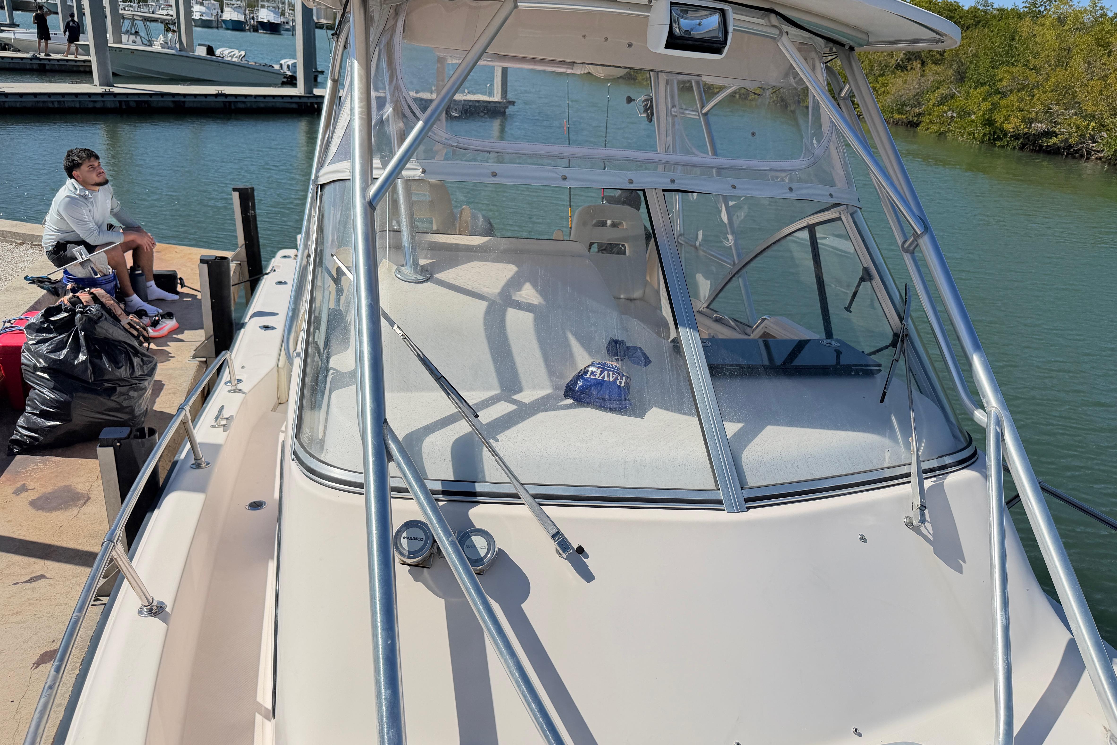 2006 Grady-White Sailfish 282 docked, with a person sitting nearby on the pier.