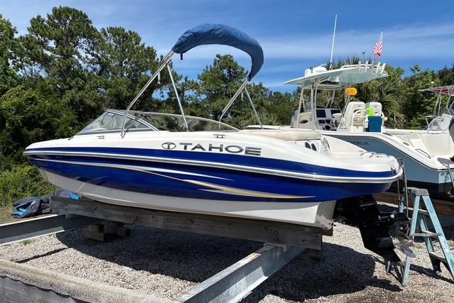 2012 Tahoe Q8 SSi boat with blue accents on a trailer, surrounded by trees and other boats.
