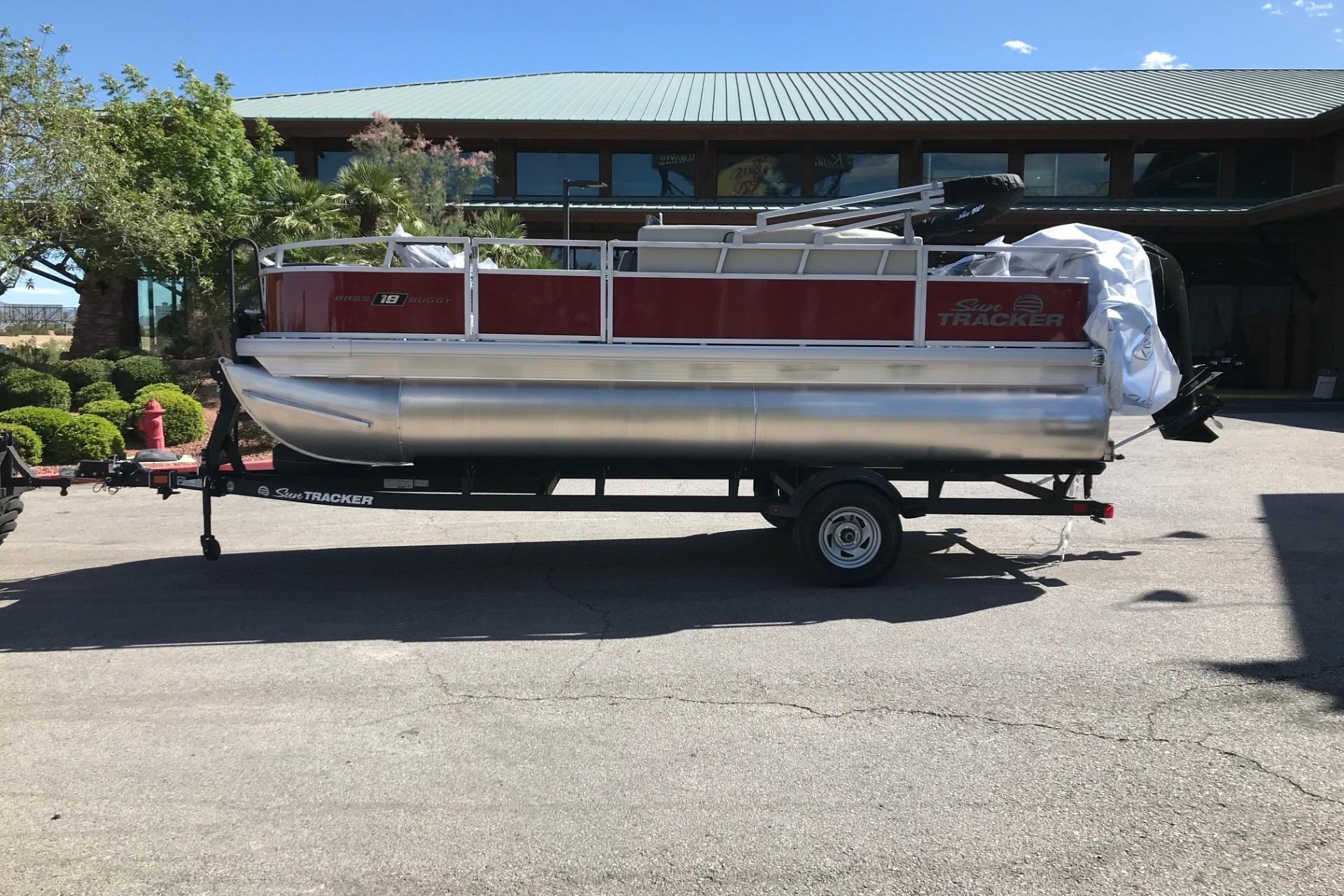 2026 Sun Tracker Bass Buggy 18 DLX pontoon boat on trailer, parked outdoors.