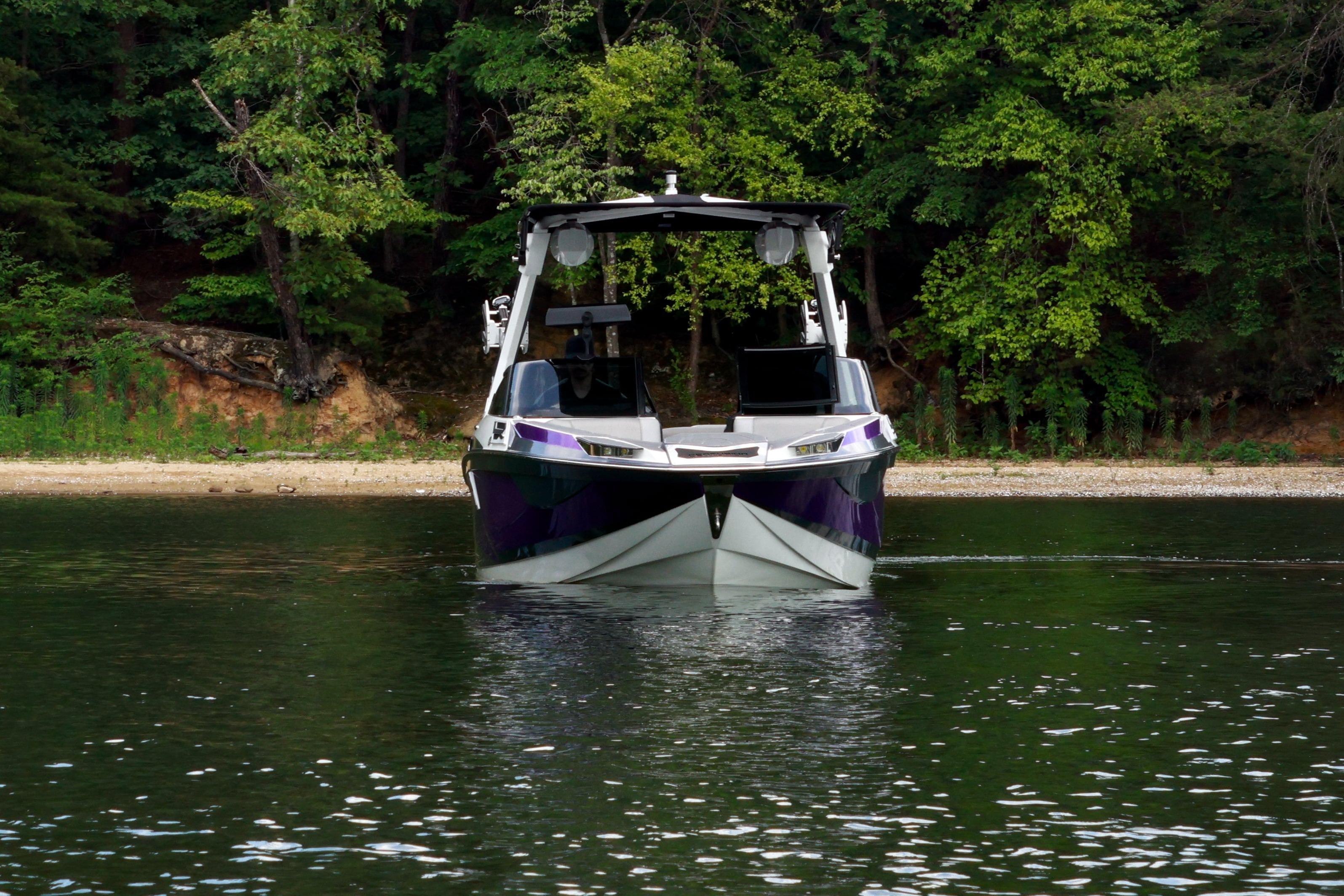 2022 Centurion Ri245 boat on calm lake near forested shoreline.