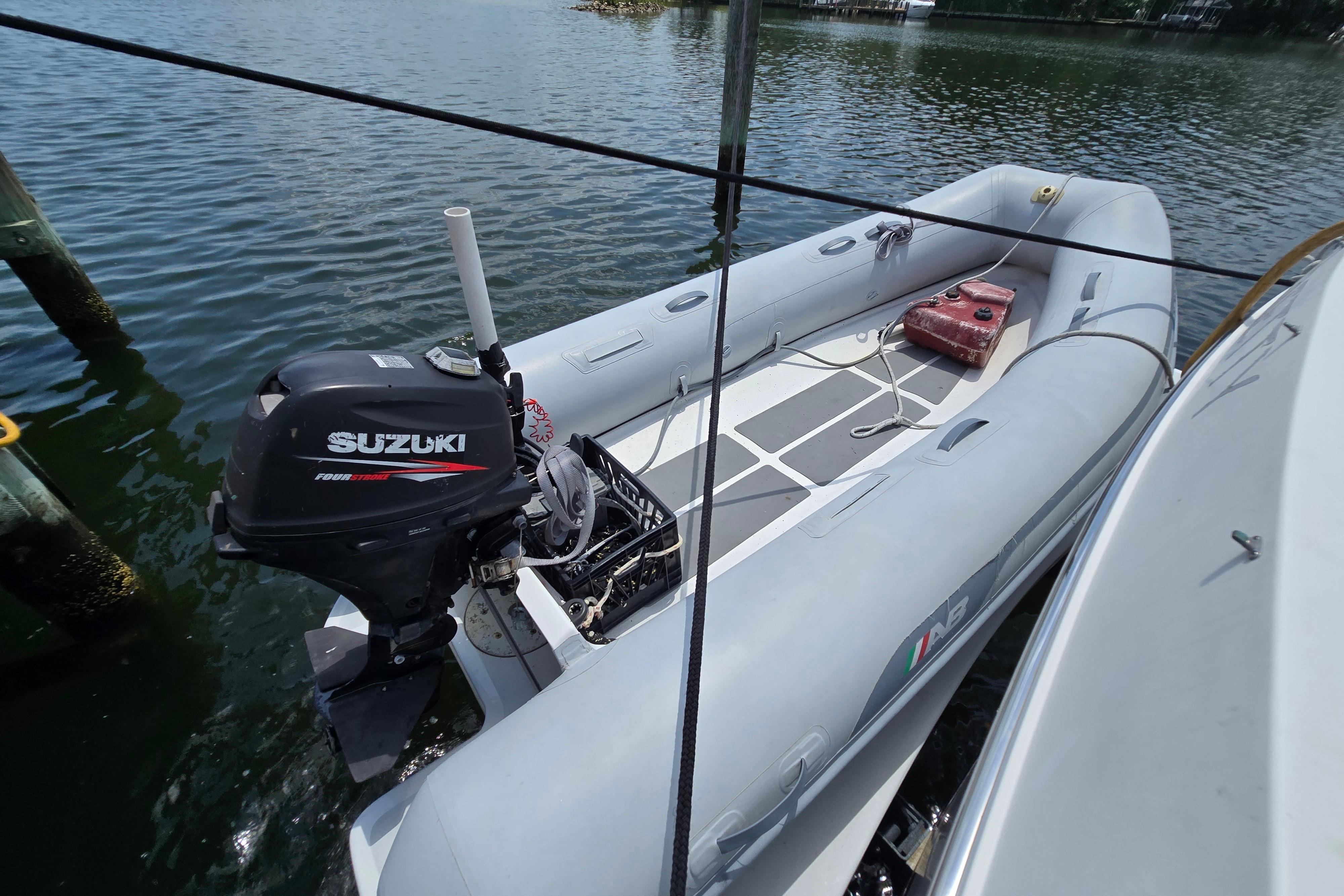 Inflatable boat with Suzuki outboard motor, docked beside a Grand Harbour 58 yacht, 2004 model.