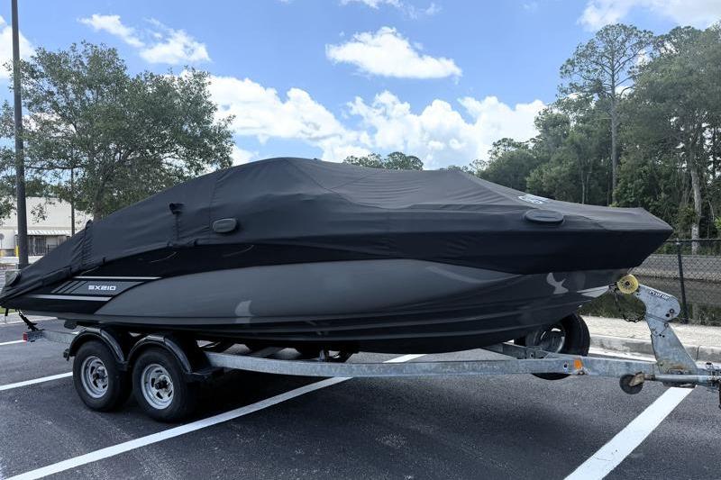 2017 Yamaha Boats SX210 covered on trailer in parking lot, under blue sky.