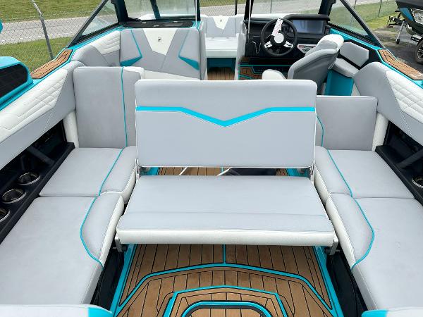 2022 Nautique S23 boat interior with gray and teal seating, wood flooring, and modern dashboard.