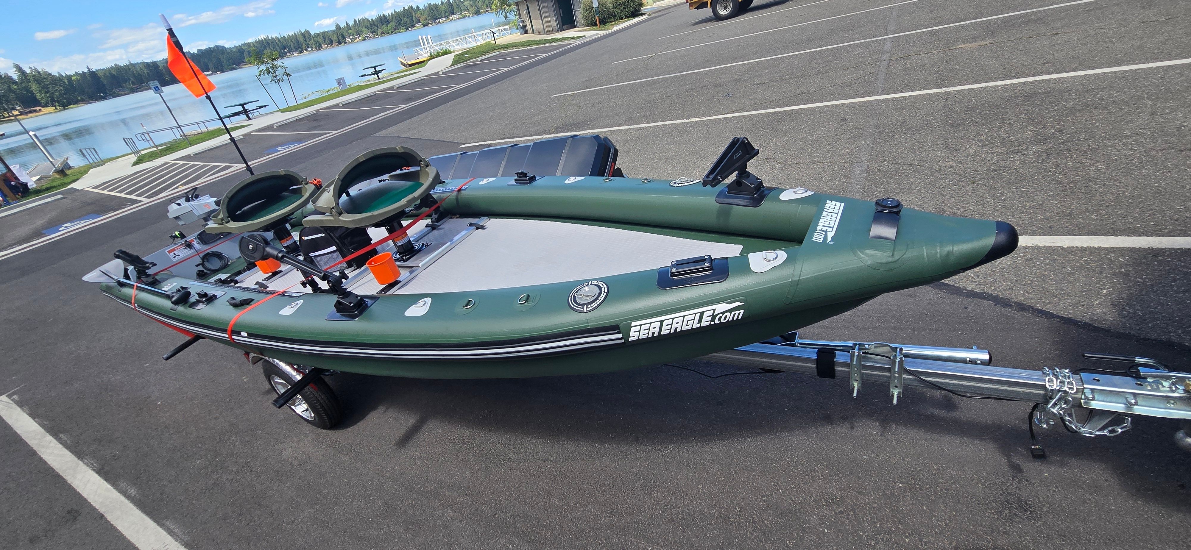 A green Sea Eagle FSK16 inflatable boat on a trailer, ready for use by the lake.