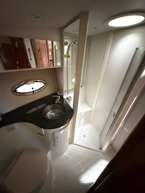 The image shows a yacht bathroom with a sink, toilet, and shower.