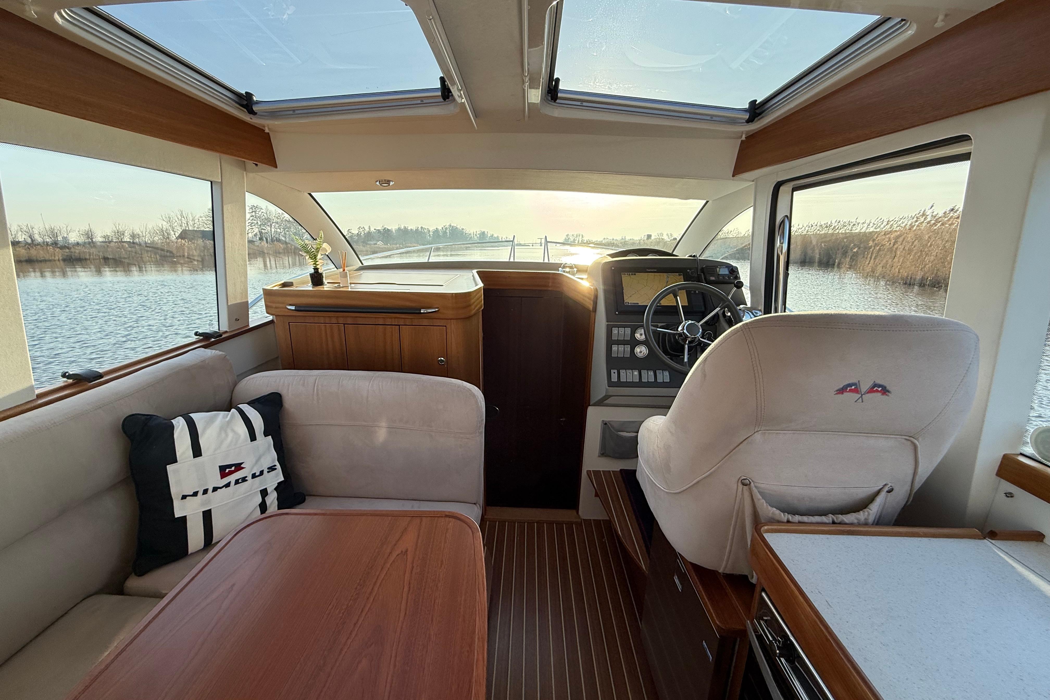 Interior of 2011 Nimbus 335 Coupe boat with helm, seating, and scenic water view.