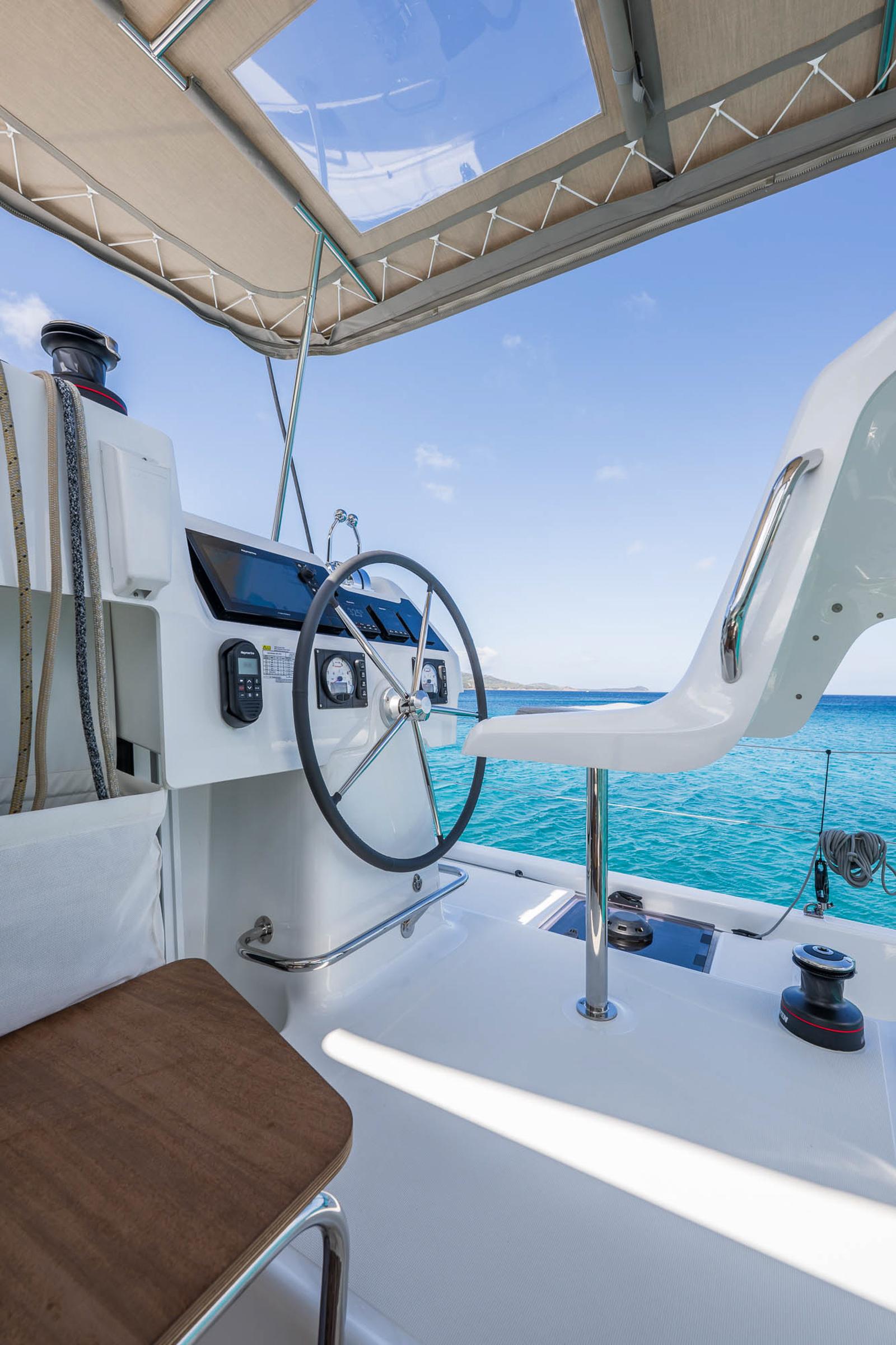 Helm of 2025 Lagoon 38 catamaran with ocean view and modern controls.