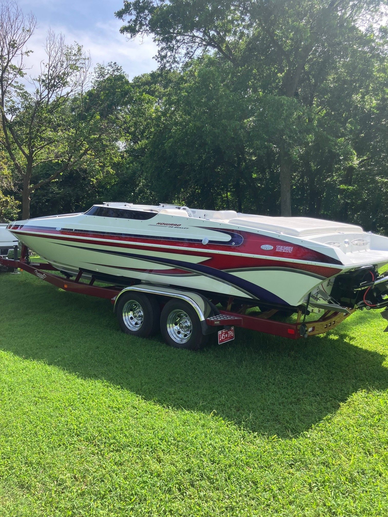 A 2003 Howard Bullet boat on a trailer, set on a grassy lawn.