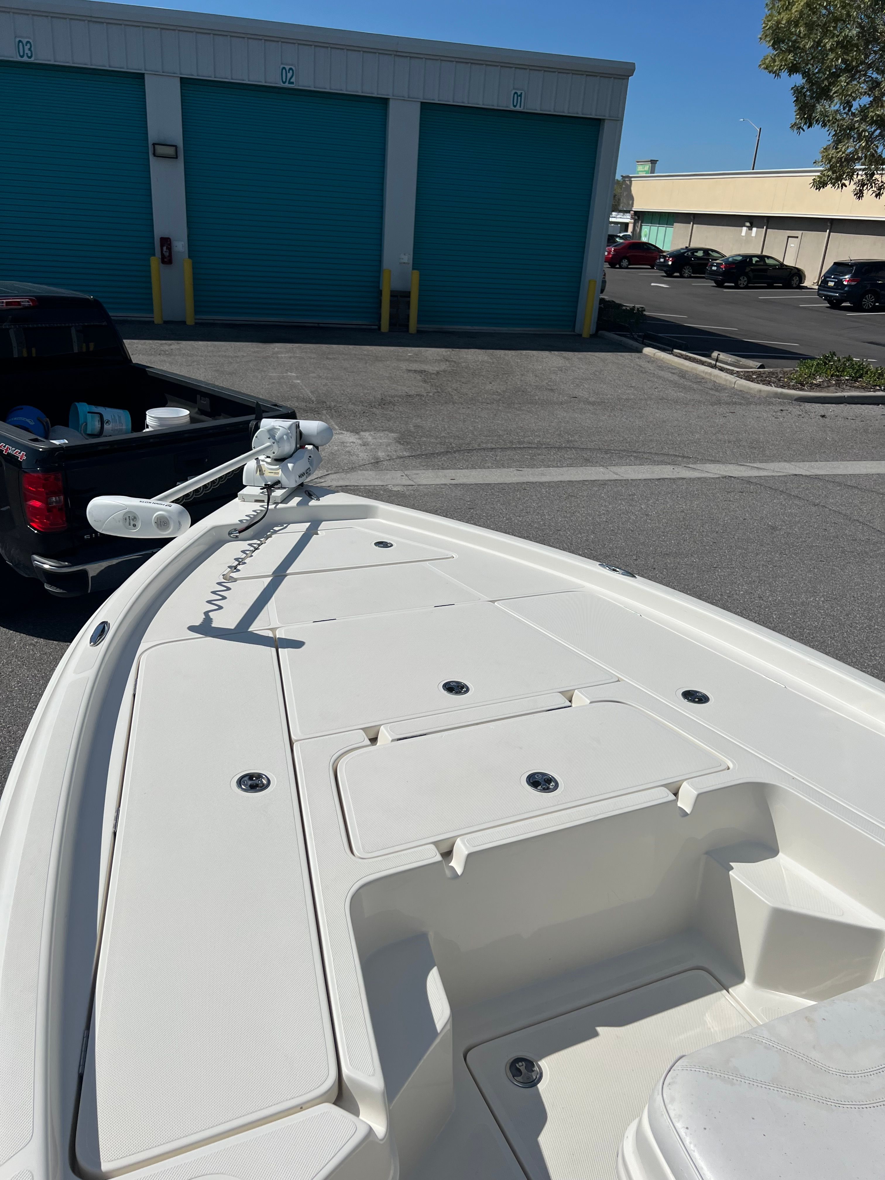 The image shows the bow of a white boat with storage compartments and a trolling motor.