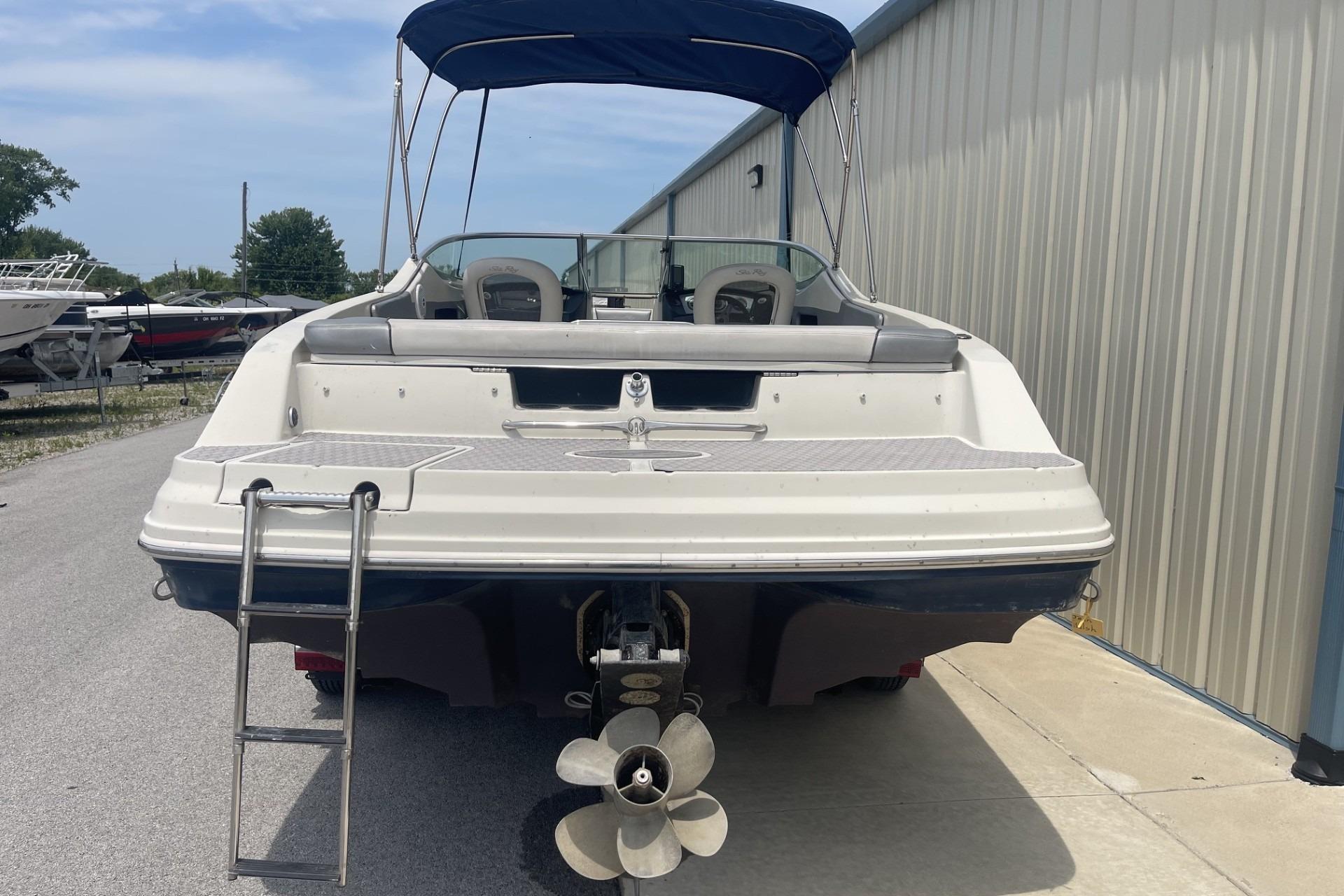 2010 Sea Ray 230 Bow Rider Select boat with ladder and canopy, docked outdoors.