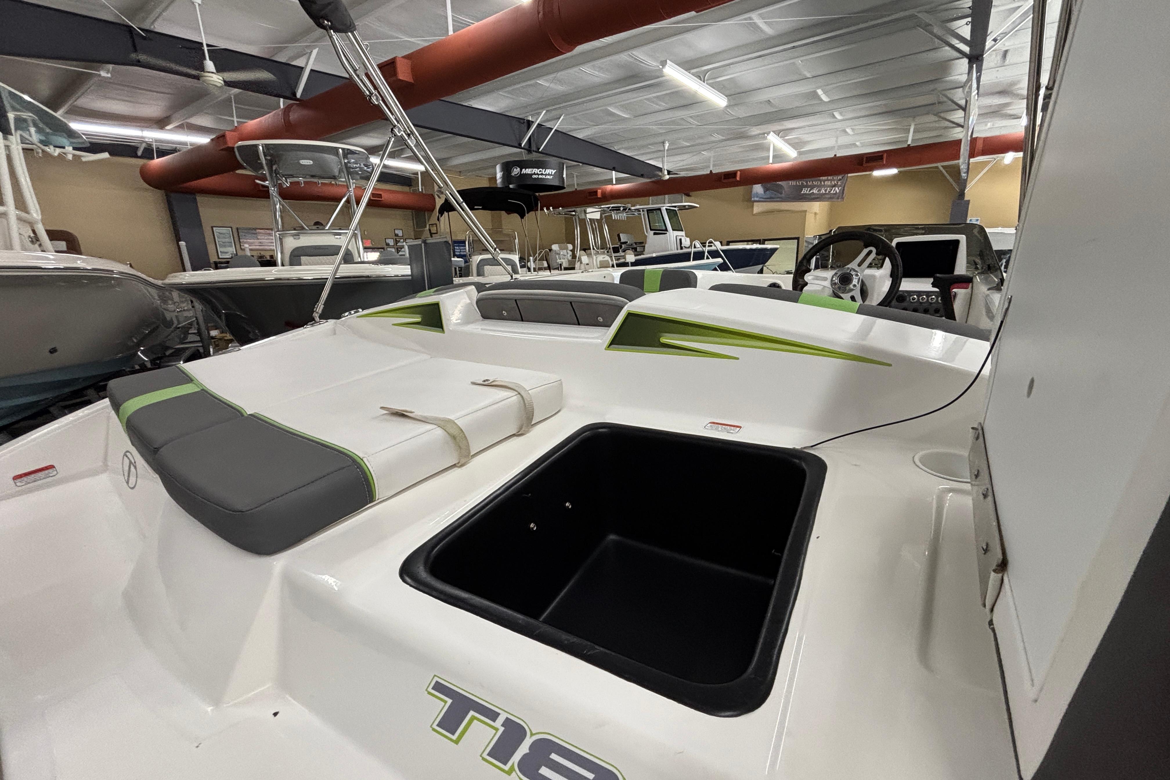 2024 Tahoe T18 boat interior with seating and storage, displayed in a showroom.