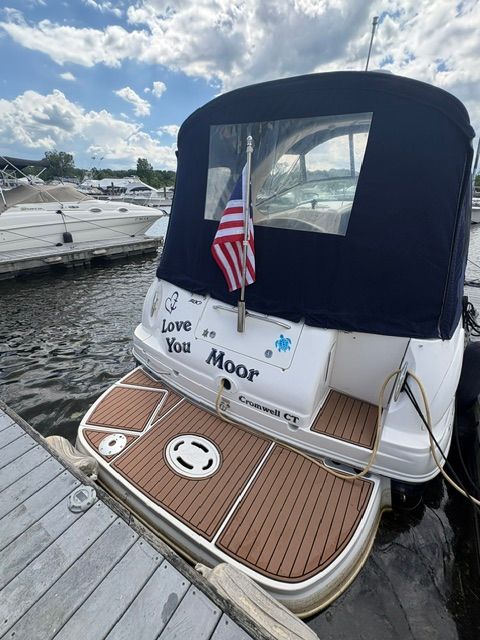 The stern of a Sea Ray Sundancer 280 boat with an American flag and a dock.