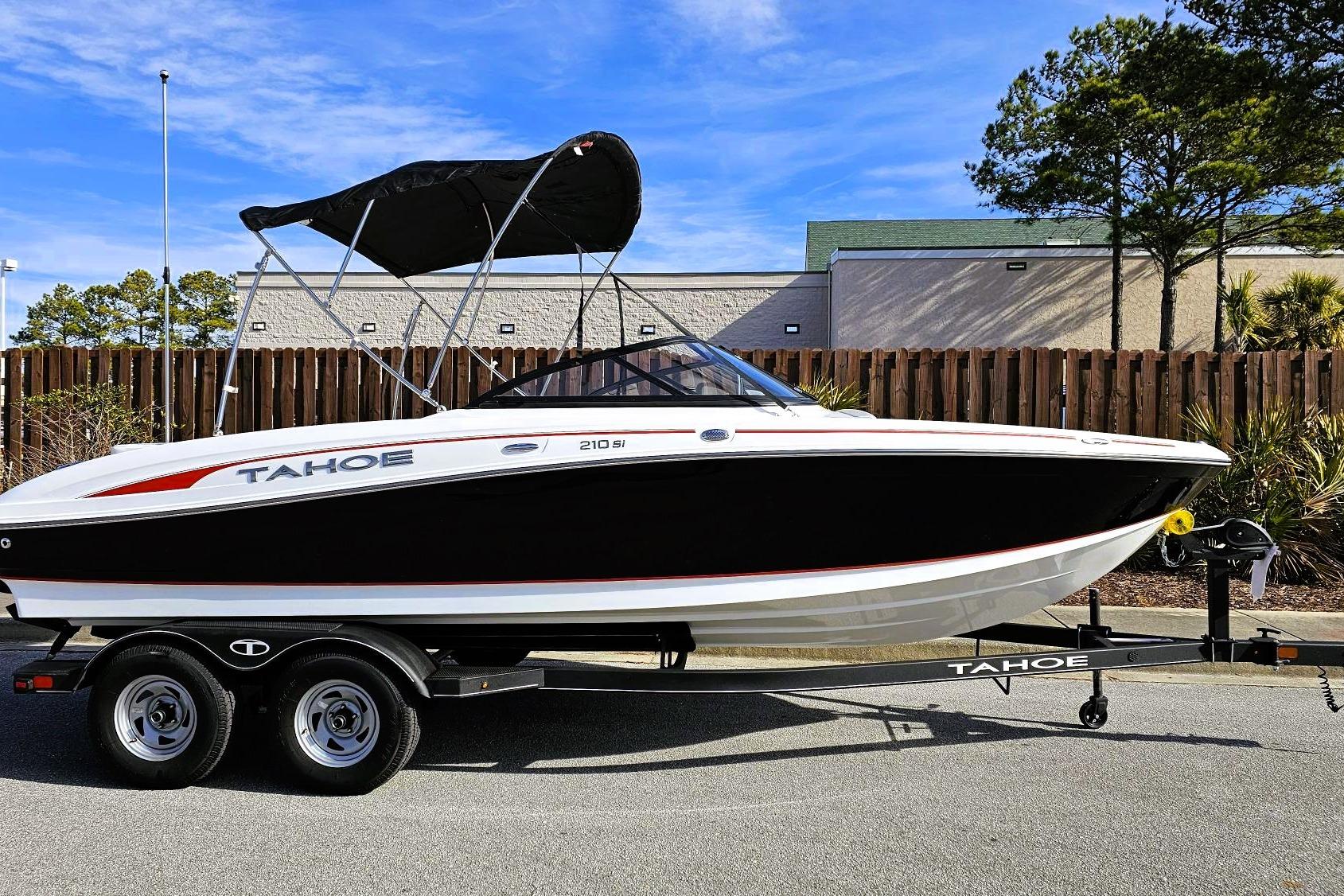 2023 Tahoe 210 Si boat on trailer, black and white design, parked outdoors.