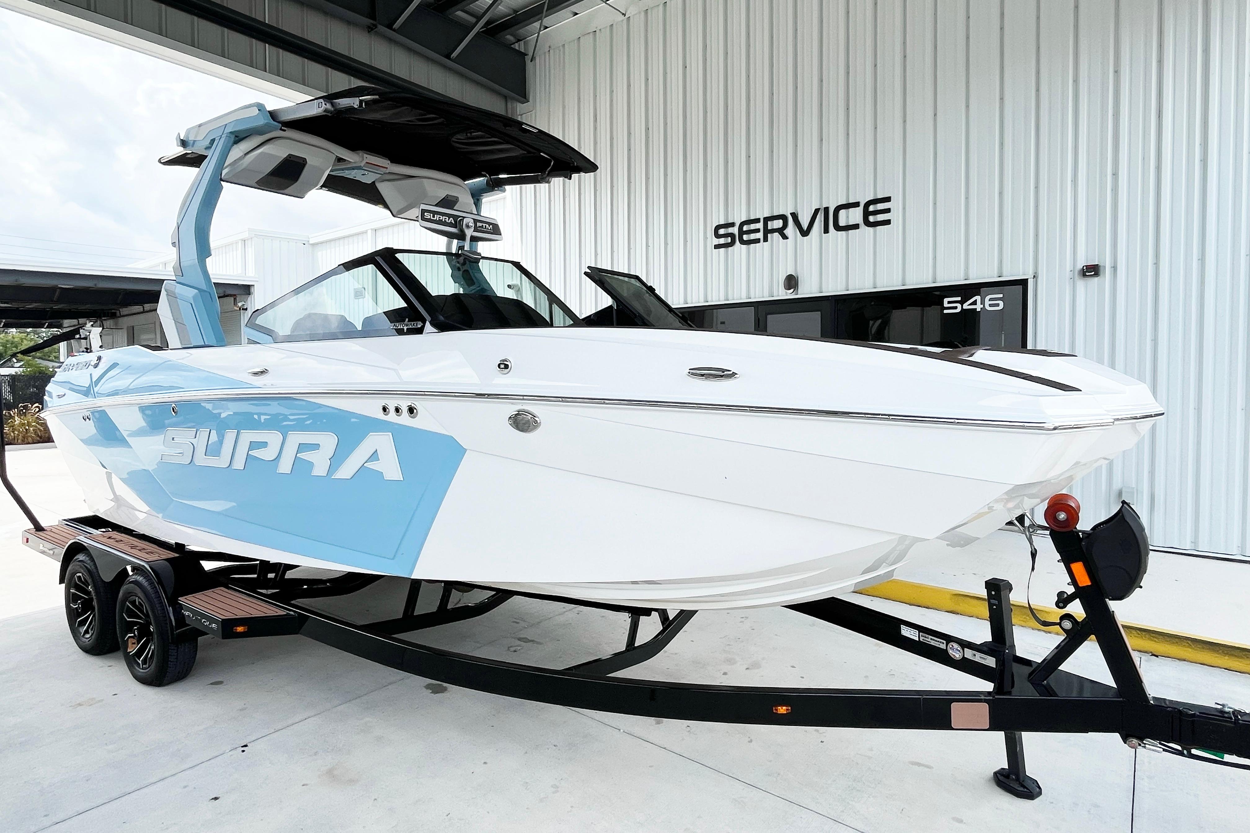 2025 Supra SA450 boat on trailer outside service center.