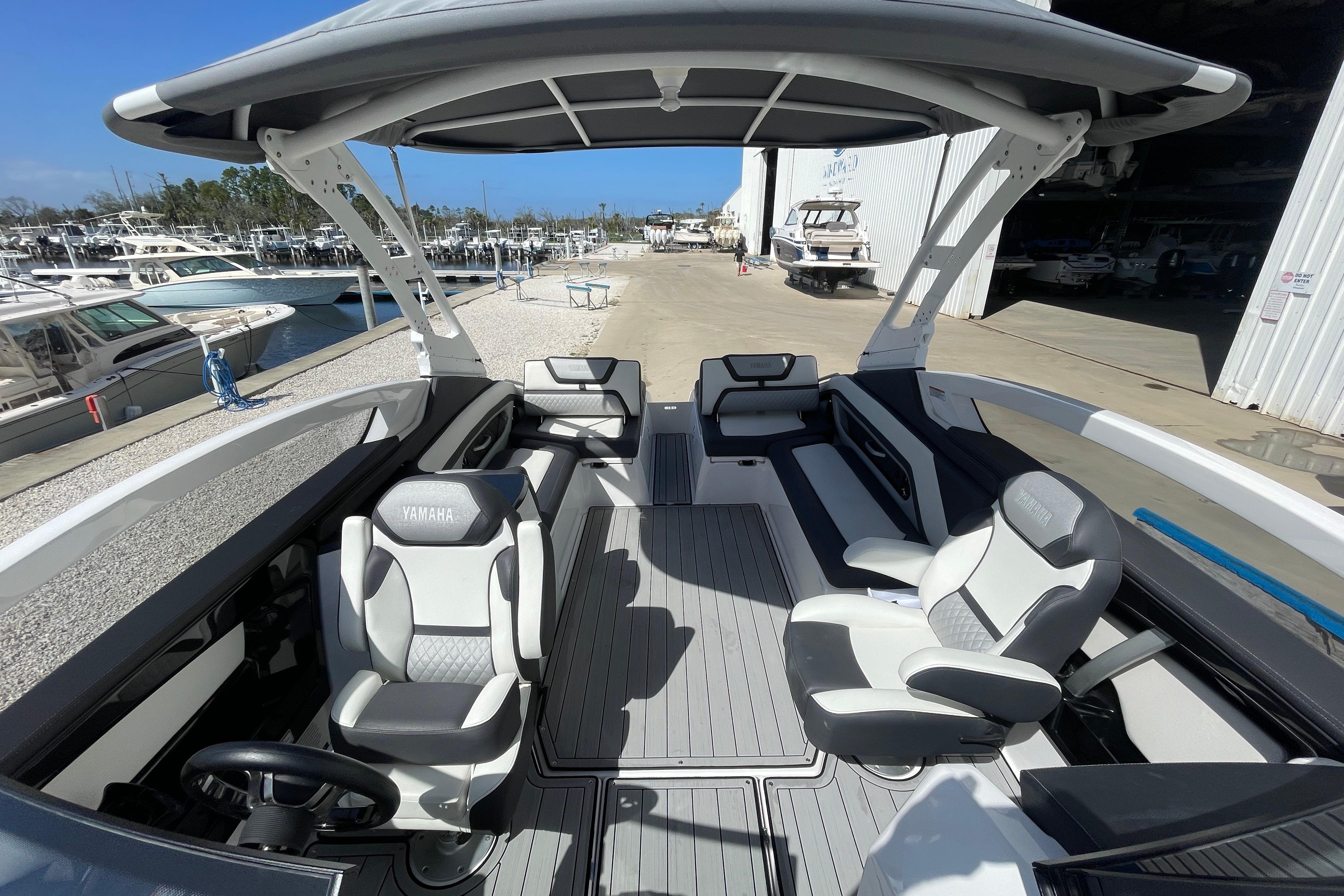 2021 Yamaha Boats 275SE interior with sleek seating and modern design at a marina.