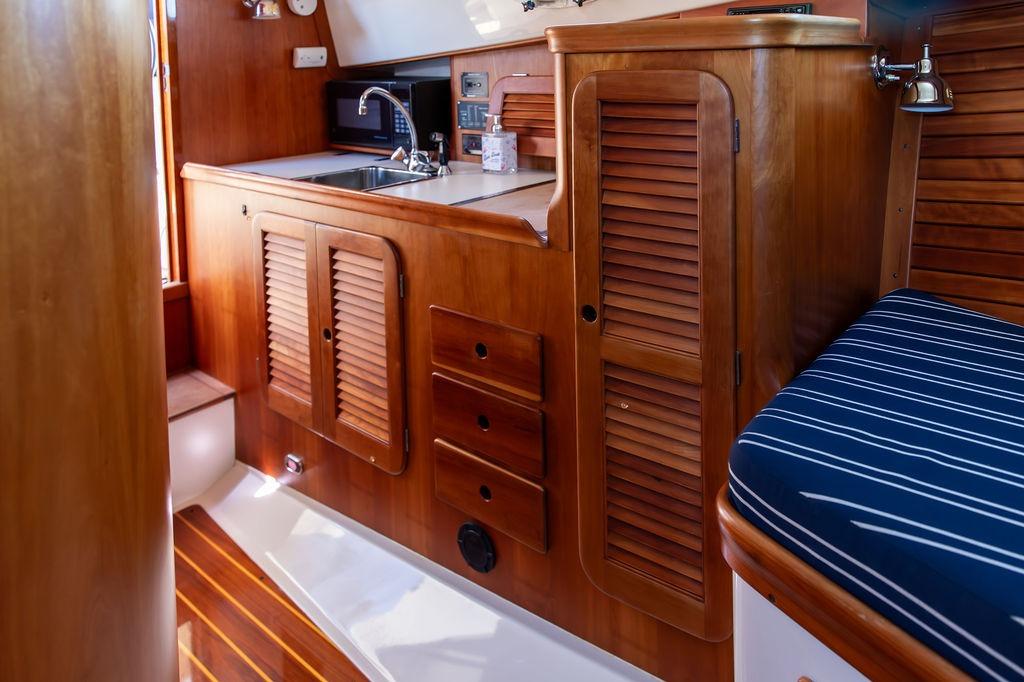 Interior of 2000 Hinckley Picnic Boat 36 Classic with wooden cabinetry and striped seating.