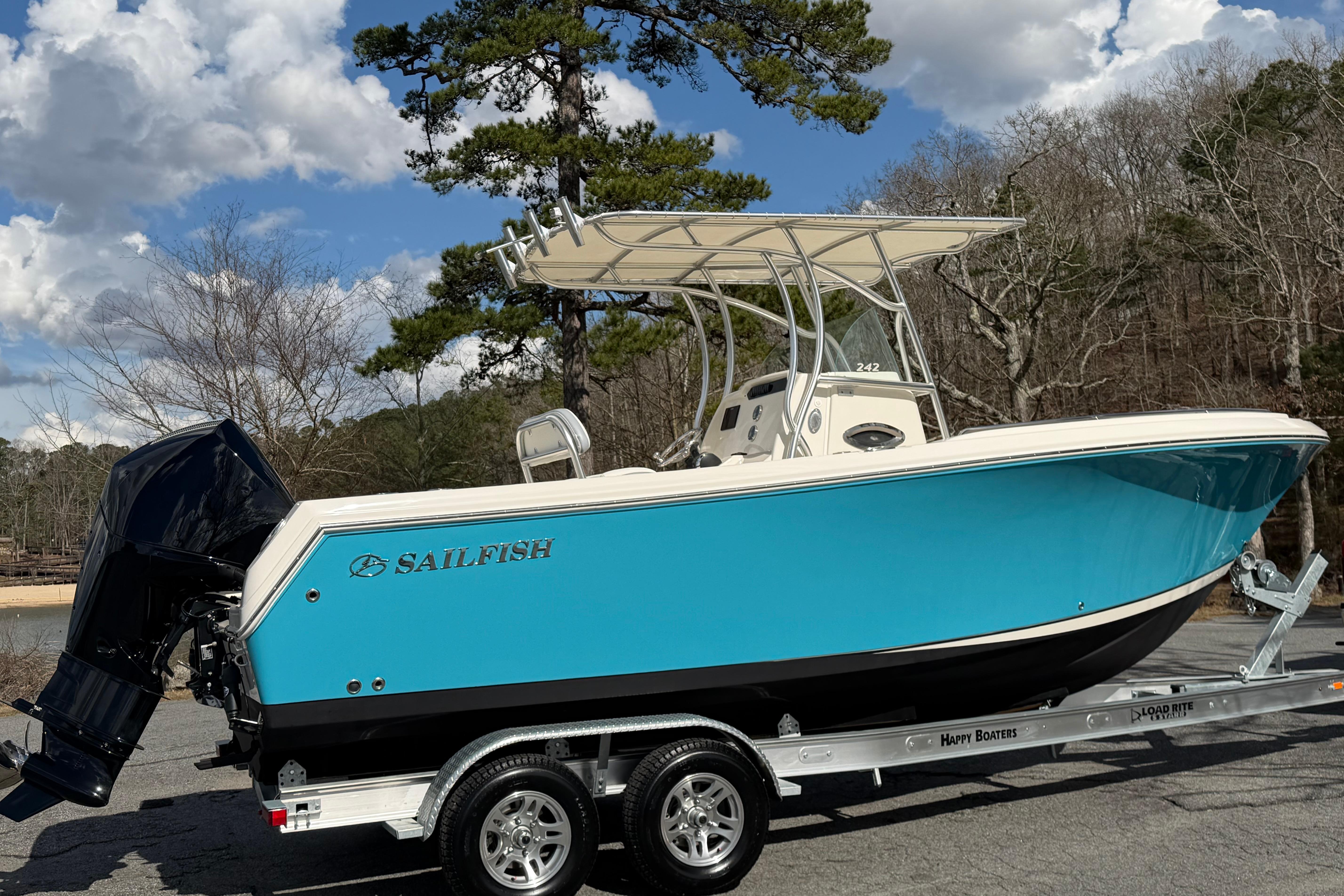 2022 Sailfish 242 CC boat on trailer, blue hull, parked outdoors under cloudy sky.