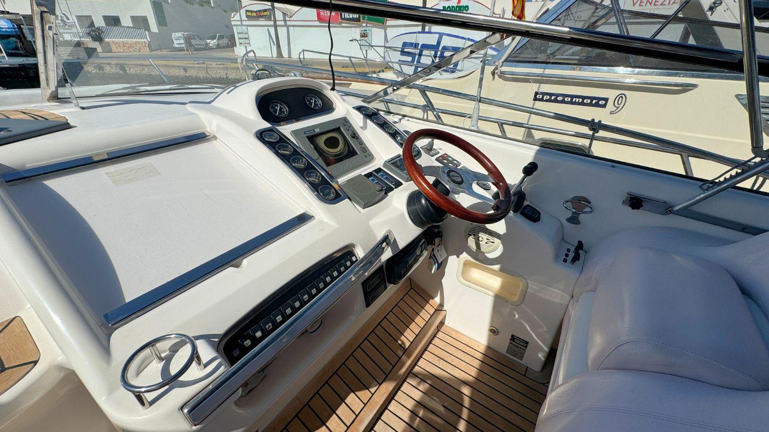 Helm of 2004 Windy 34 Khamsin boat with wooden steering wheel and modern controls.