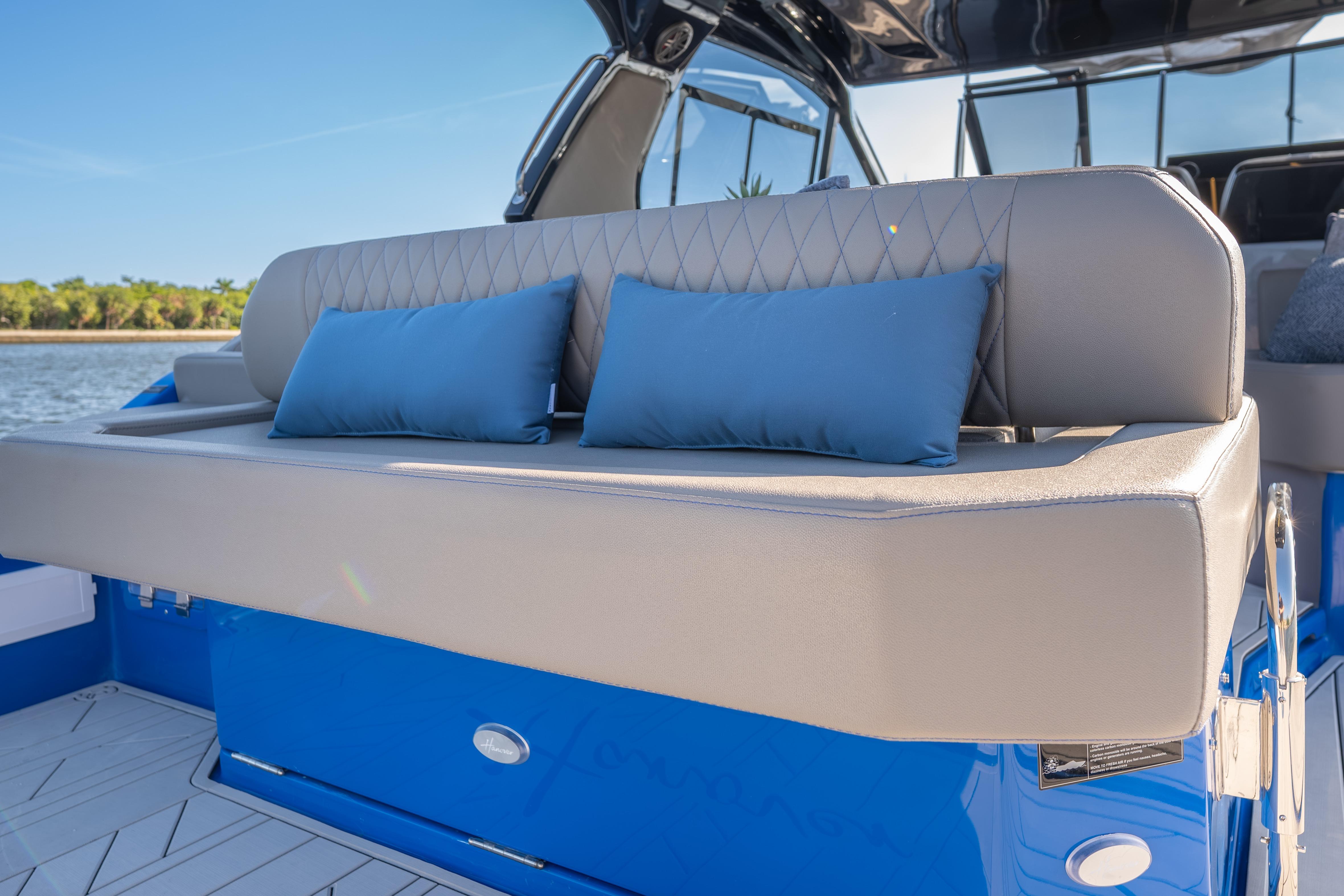 Luxurious seating on 2026 Hanover 347 boat with blue cushions, docked by the water.