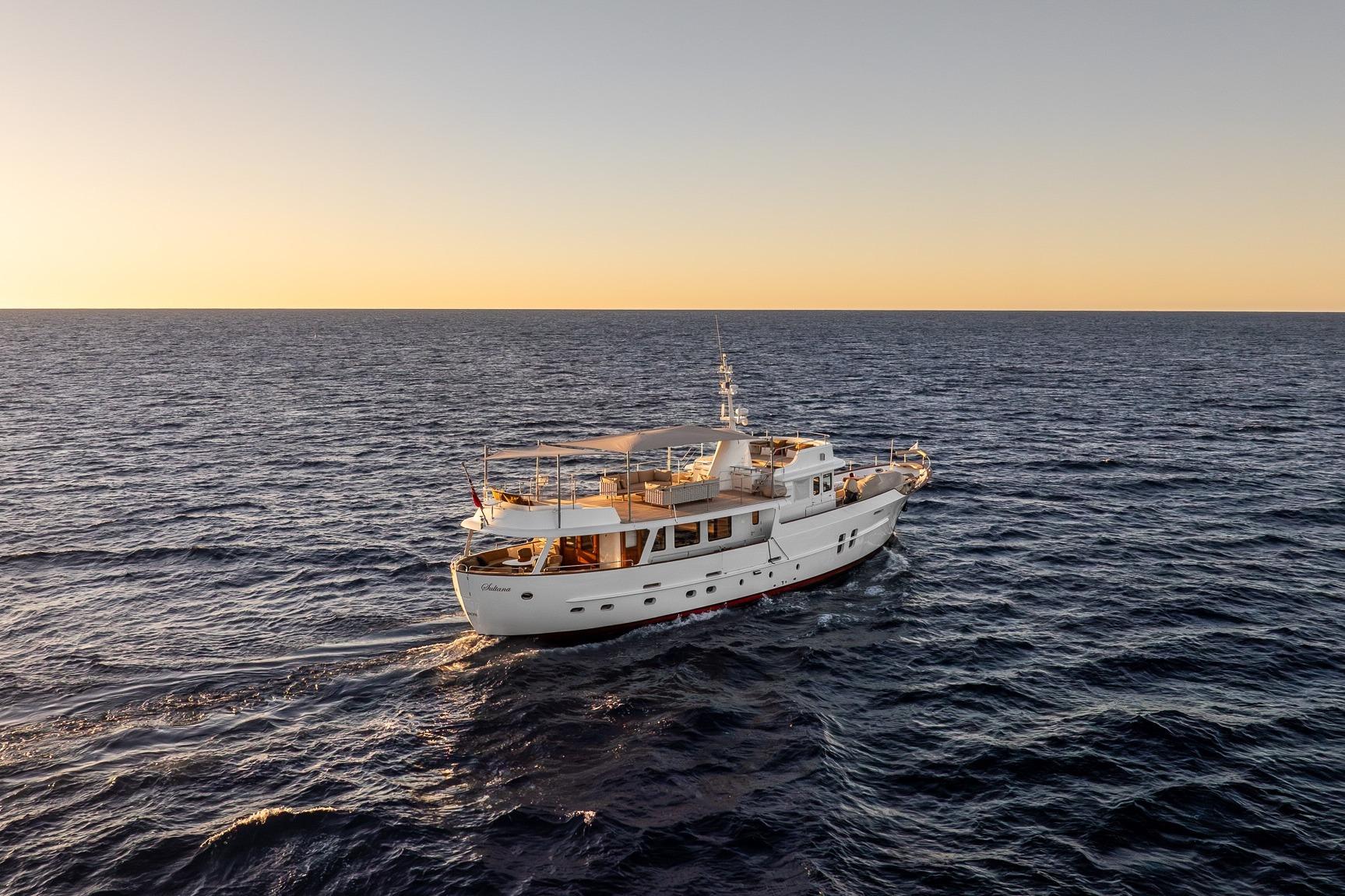 Vintage 1969 Feadship 25.8m yacht cruising at sunset on open sea.