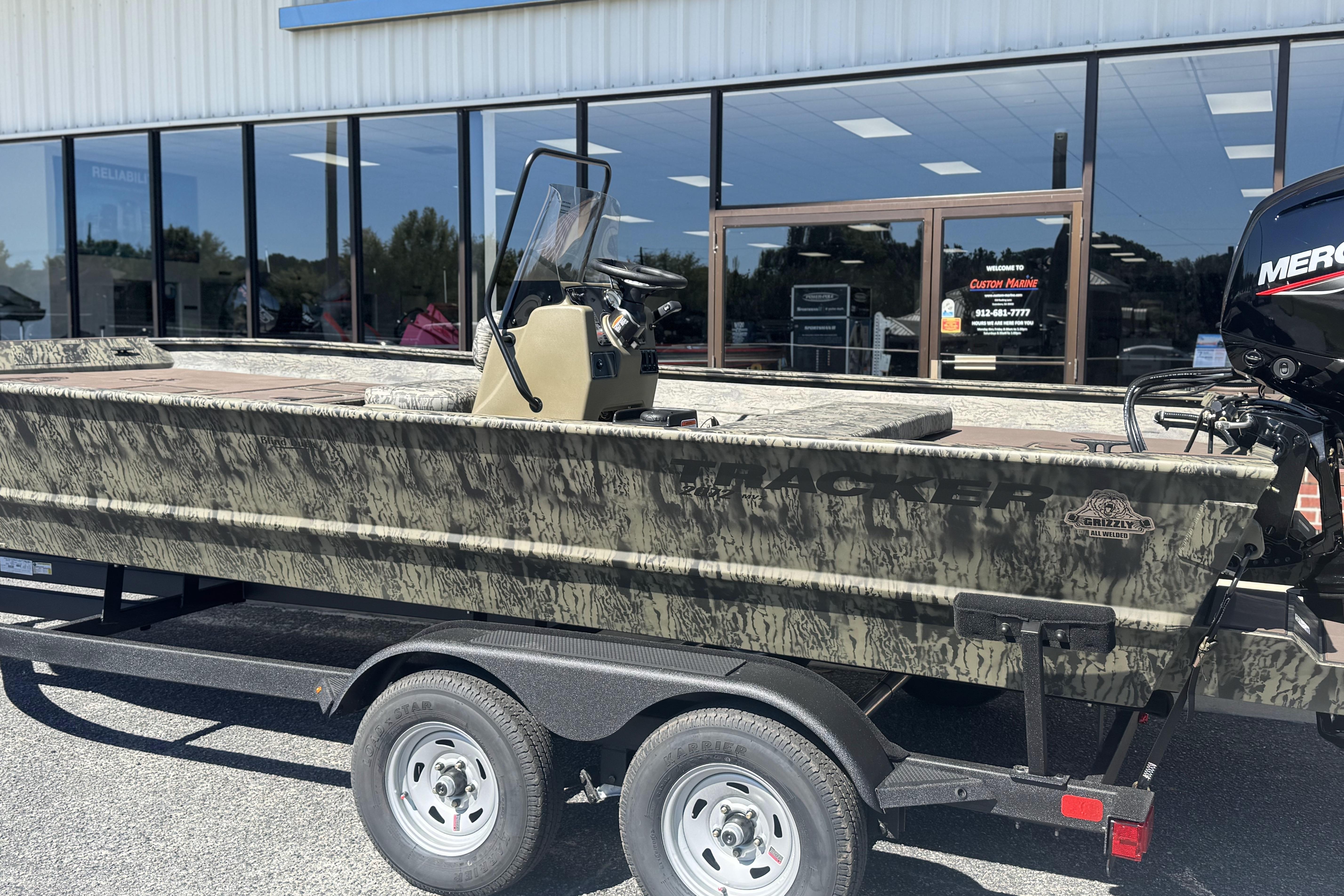 2026 Tracker Grizzly 2072 CC boat on trailer outside a marine store.