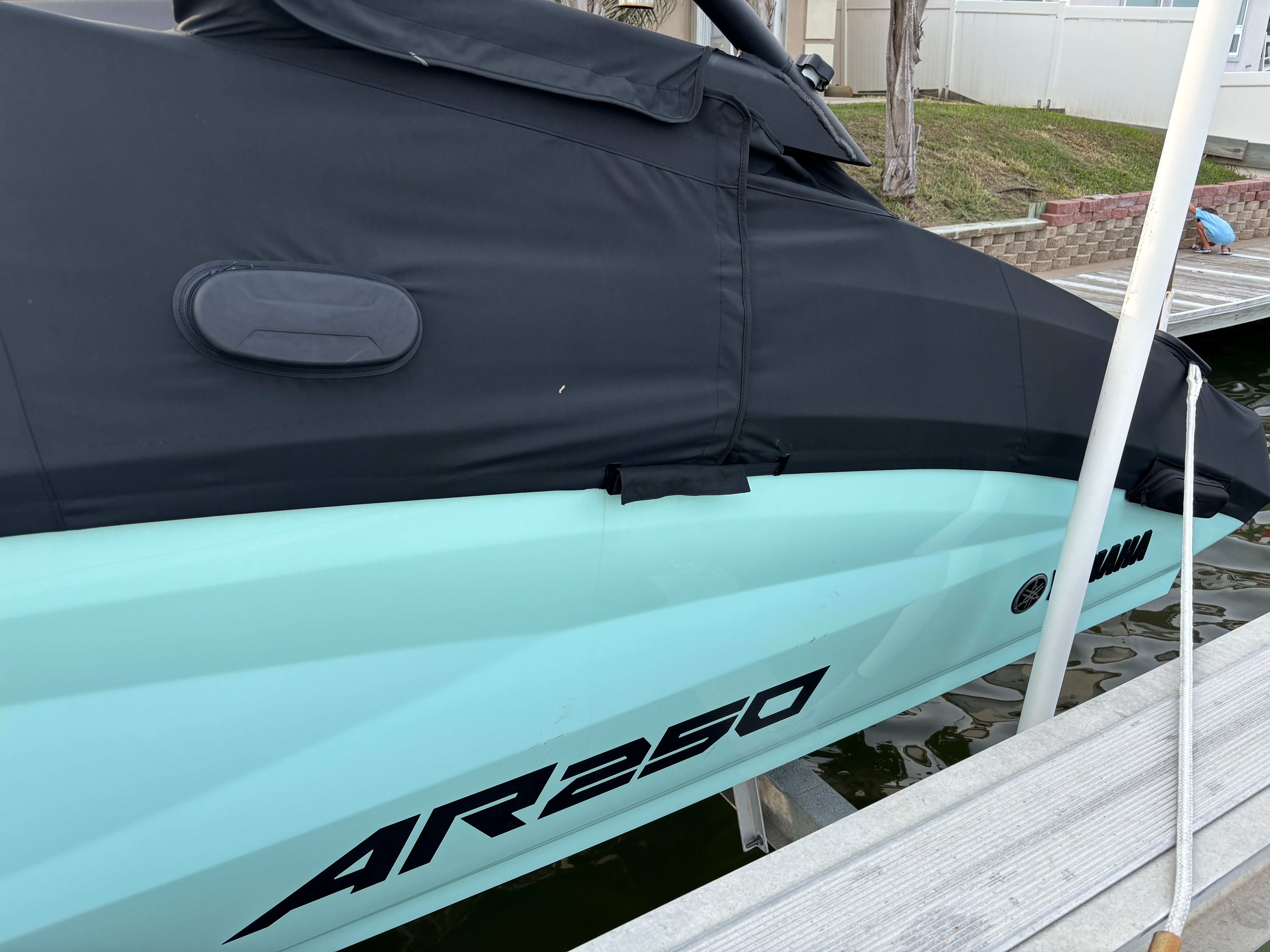 A Yamaha AR250 boat is docked, partially covered with a black cover.