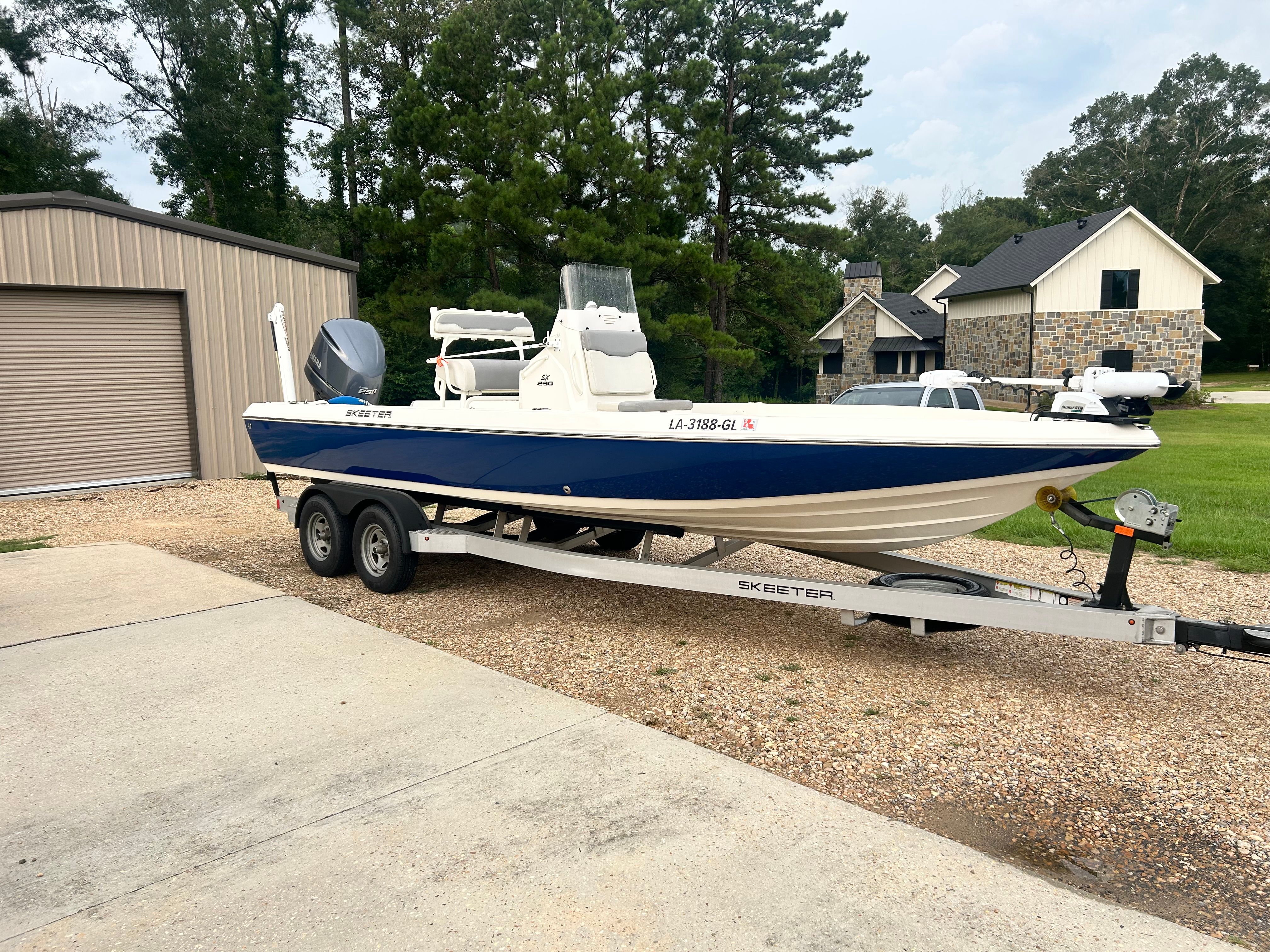 A 2016 Skeeter SX230 boat on a trailer in a driveway.