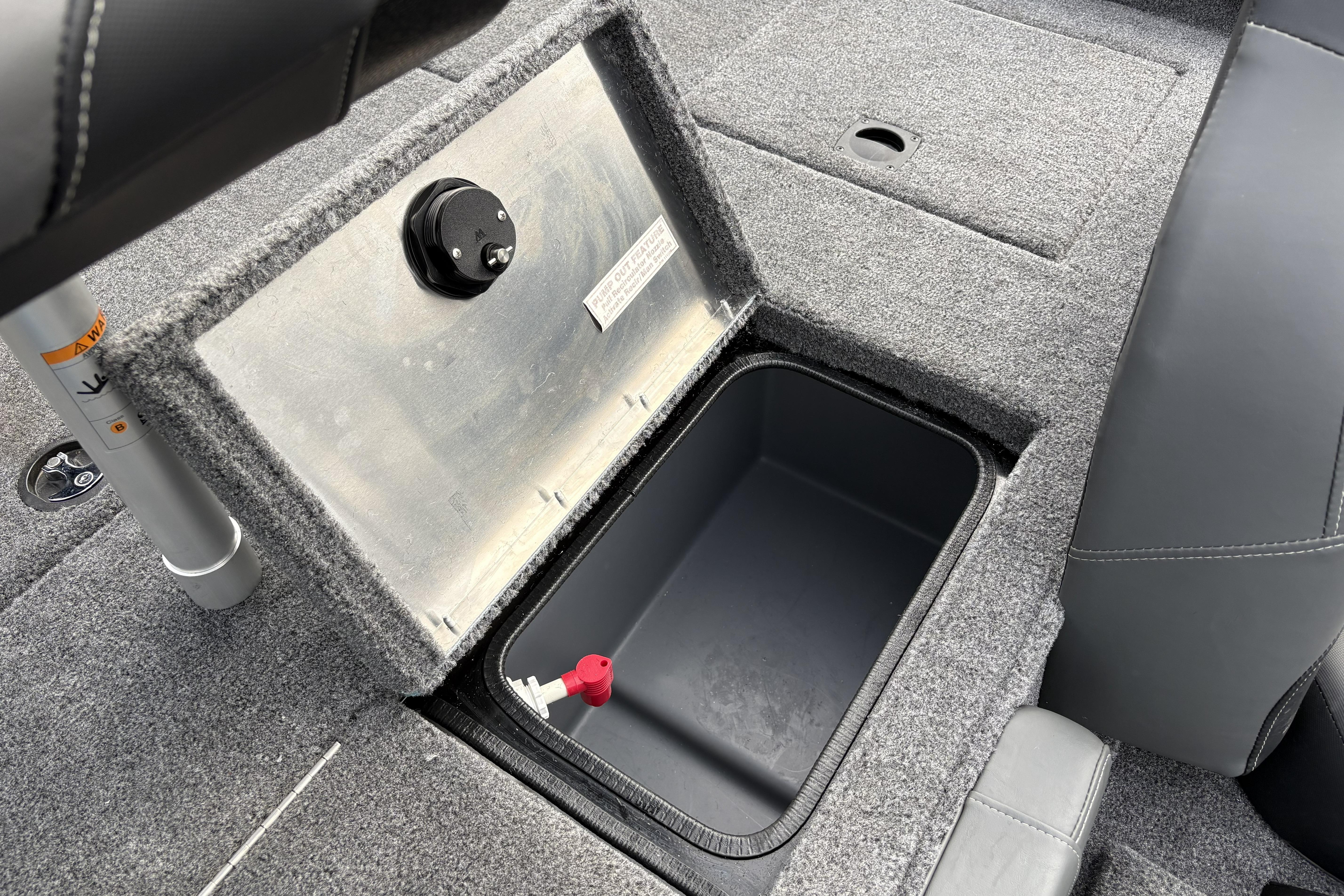 Open storage compartment in 2026 Tracker Pro Team 195 boat, featuring carpeted interior.