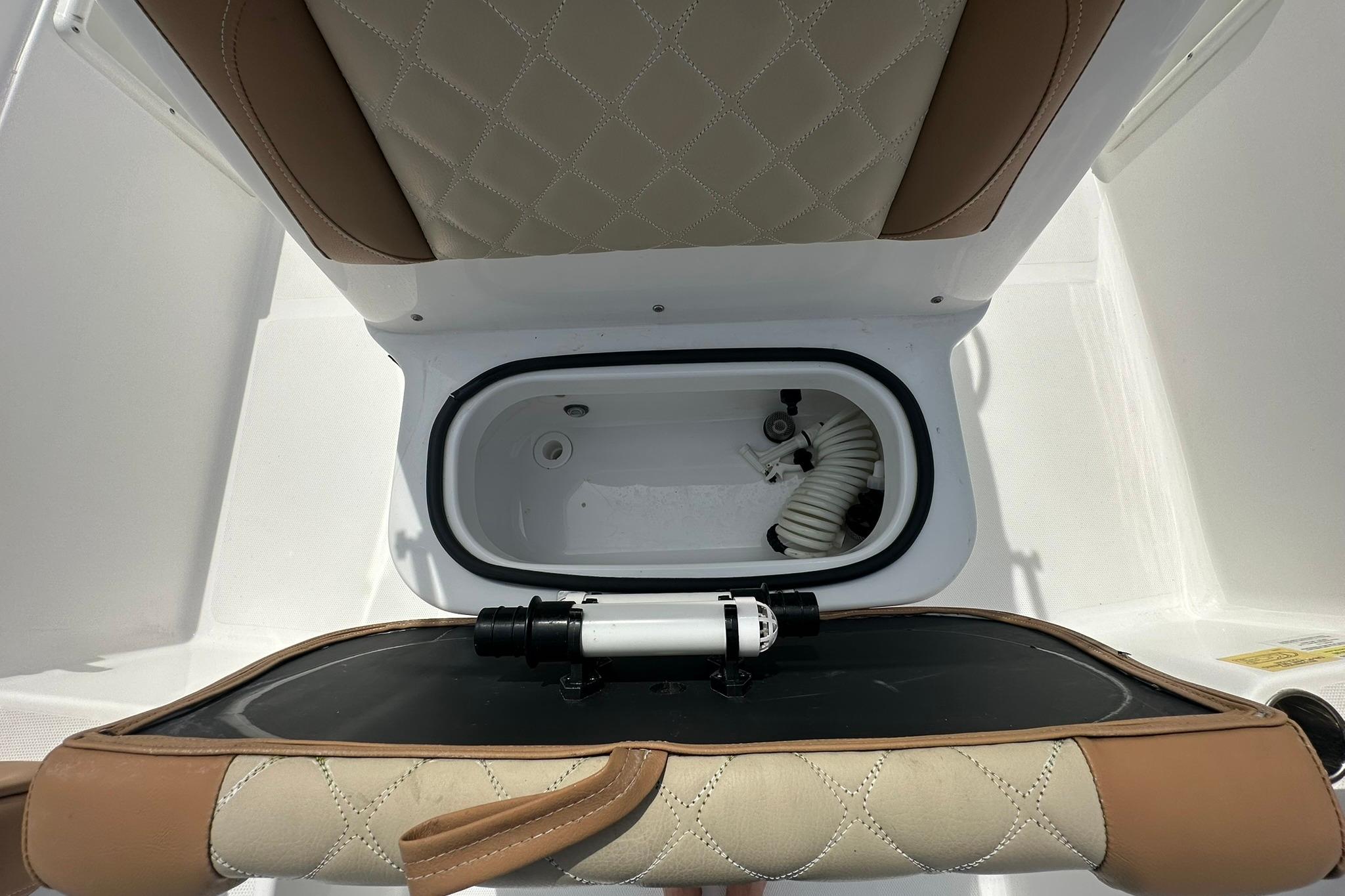 2024 NauticStar 211 Hybrid boat seat with storage compartment and hose.