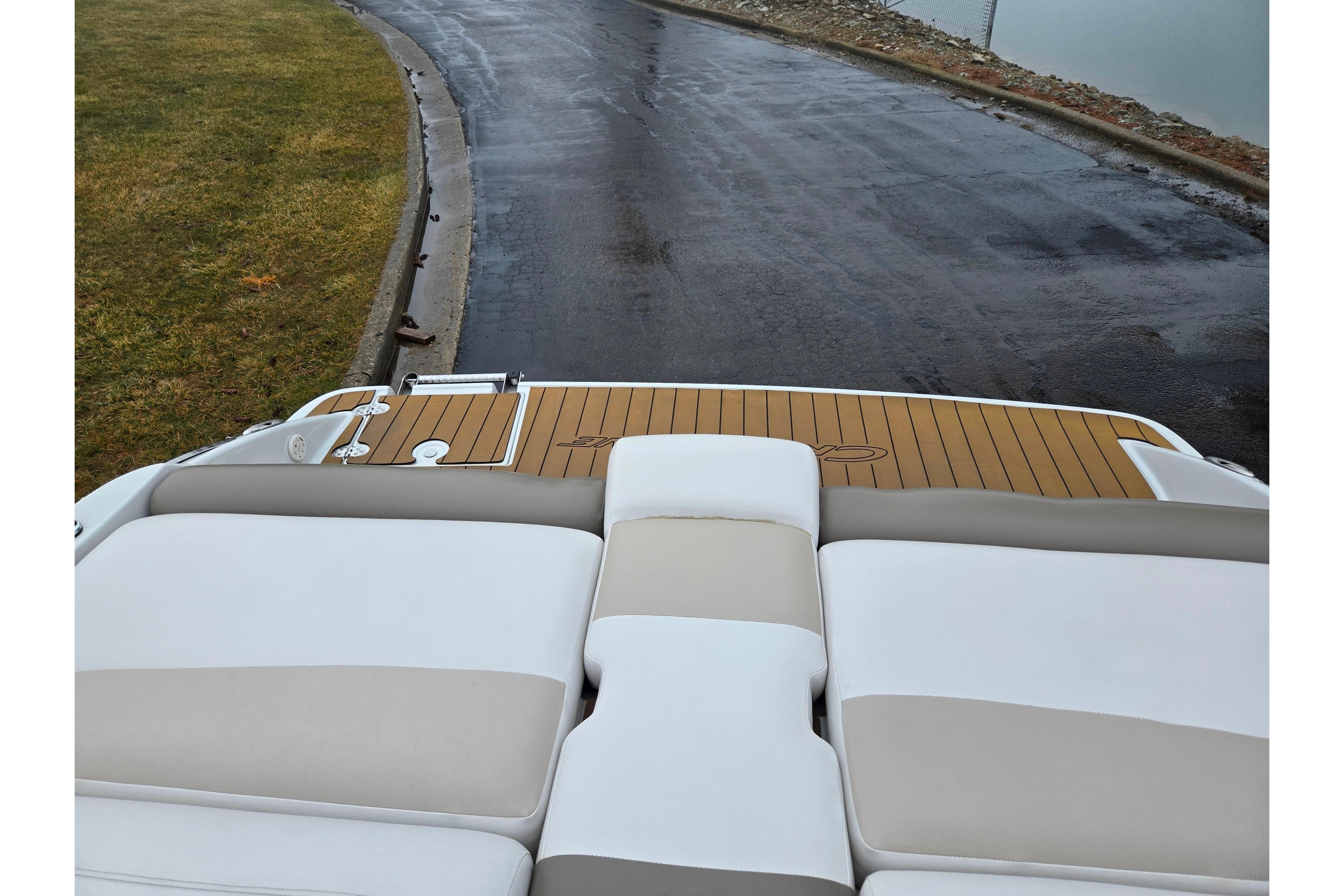 2012 Crownline 235 SS boat with cushioned seating and wooden deck, near a wet road.