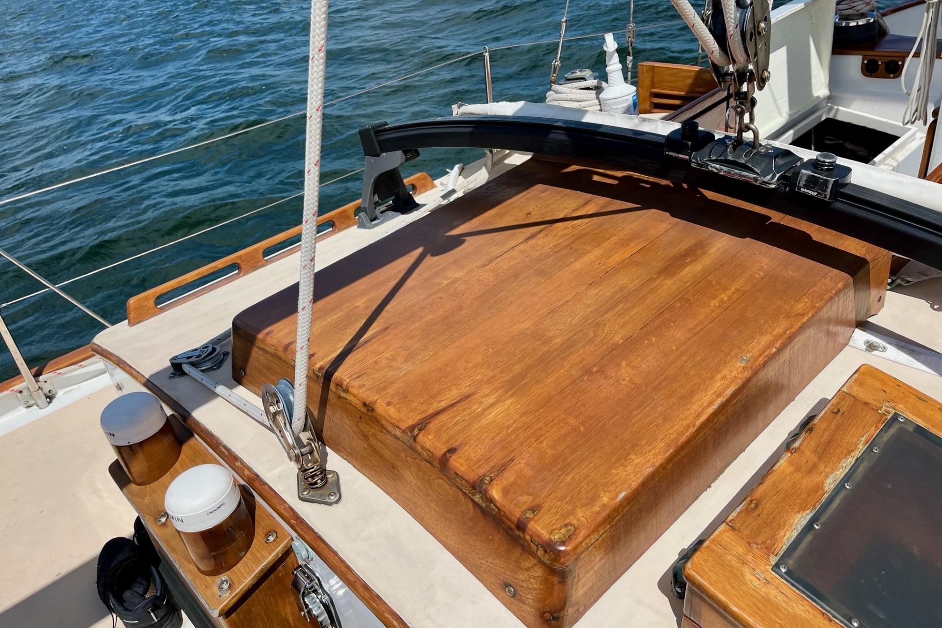 Wooden deck of 1979 Cherubini 44 sailboat with ocean backdrop.