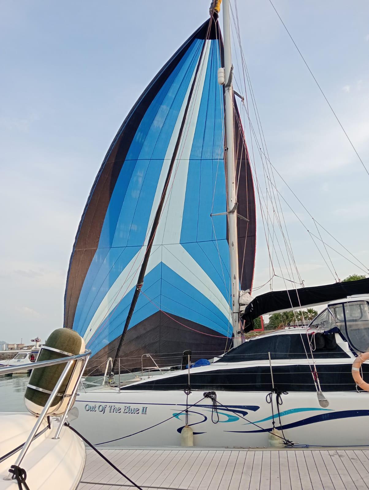 Sailboat "Out of the Blue II" with vibrant blue sail, Lightwave 38, 2007 model, docked at marina.