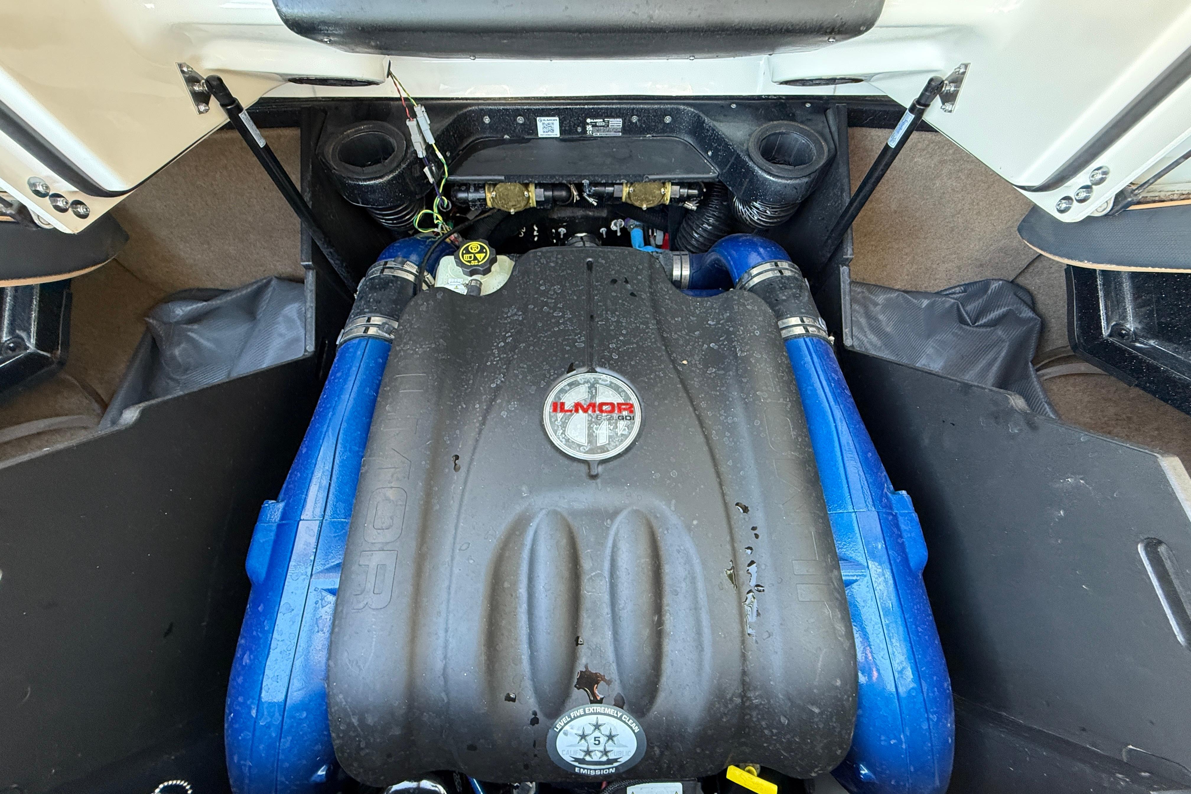 2023 MasterCraft X22 engine compartment with Ilmor engine, featuring blue hoses and black cover.