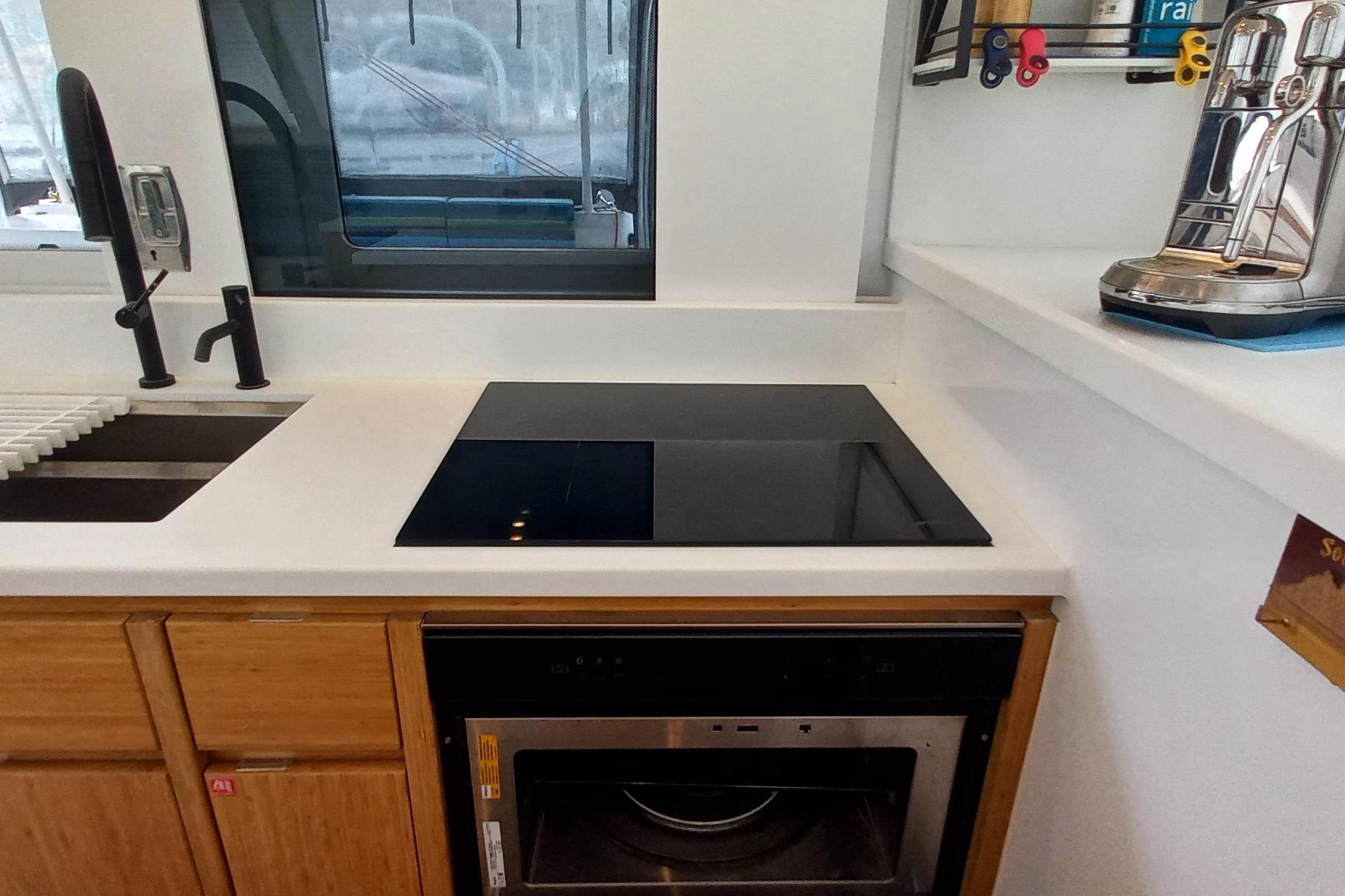 Modern kitchen with induction cooktop, sink, and espresso machine in a 2022 Balance 482 model.