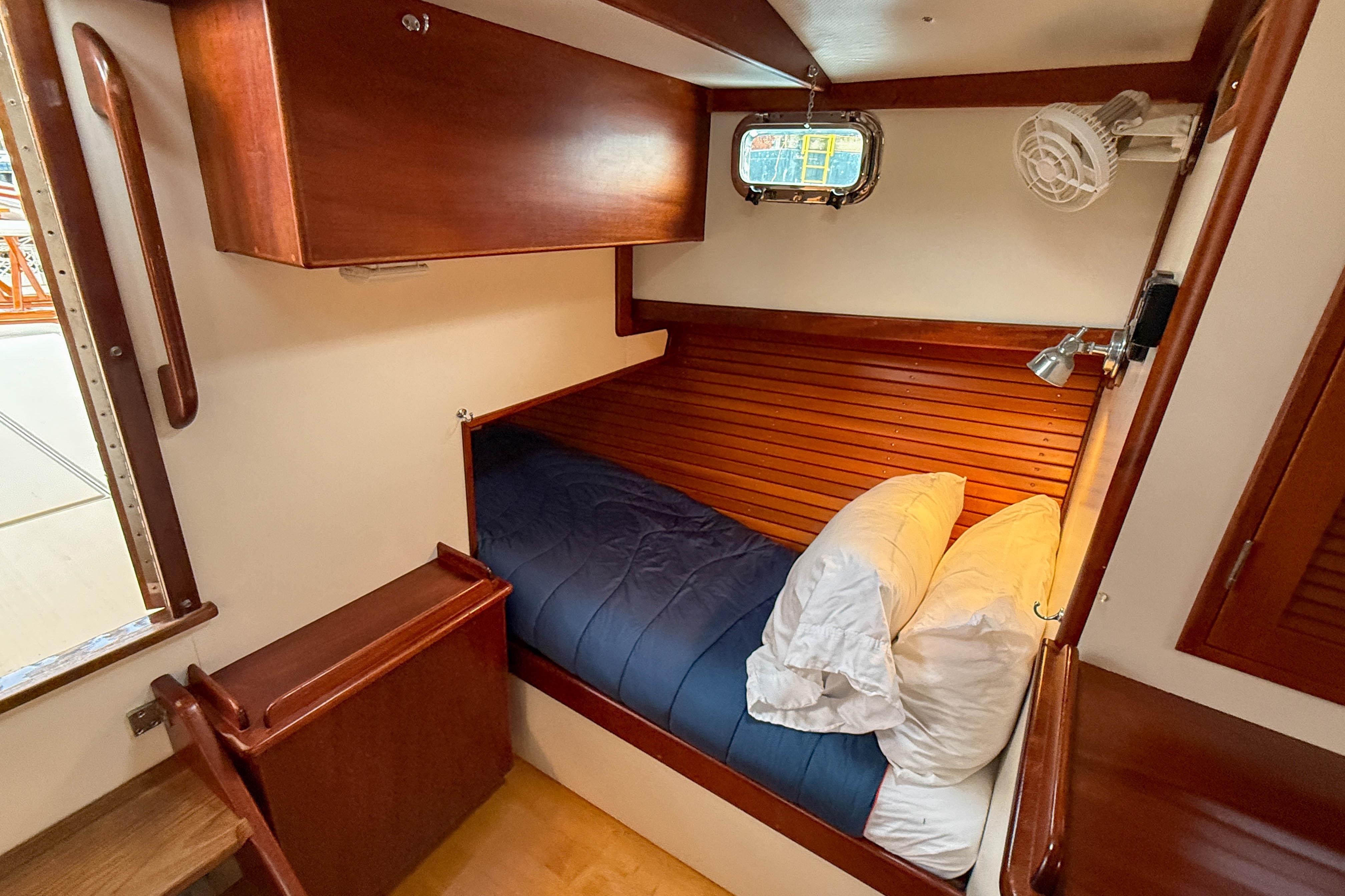 Cozy cabin interior of 2003 John Williams Stanley 38 with wooden accents and bedding.