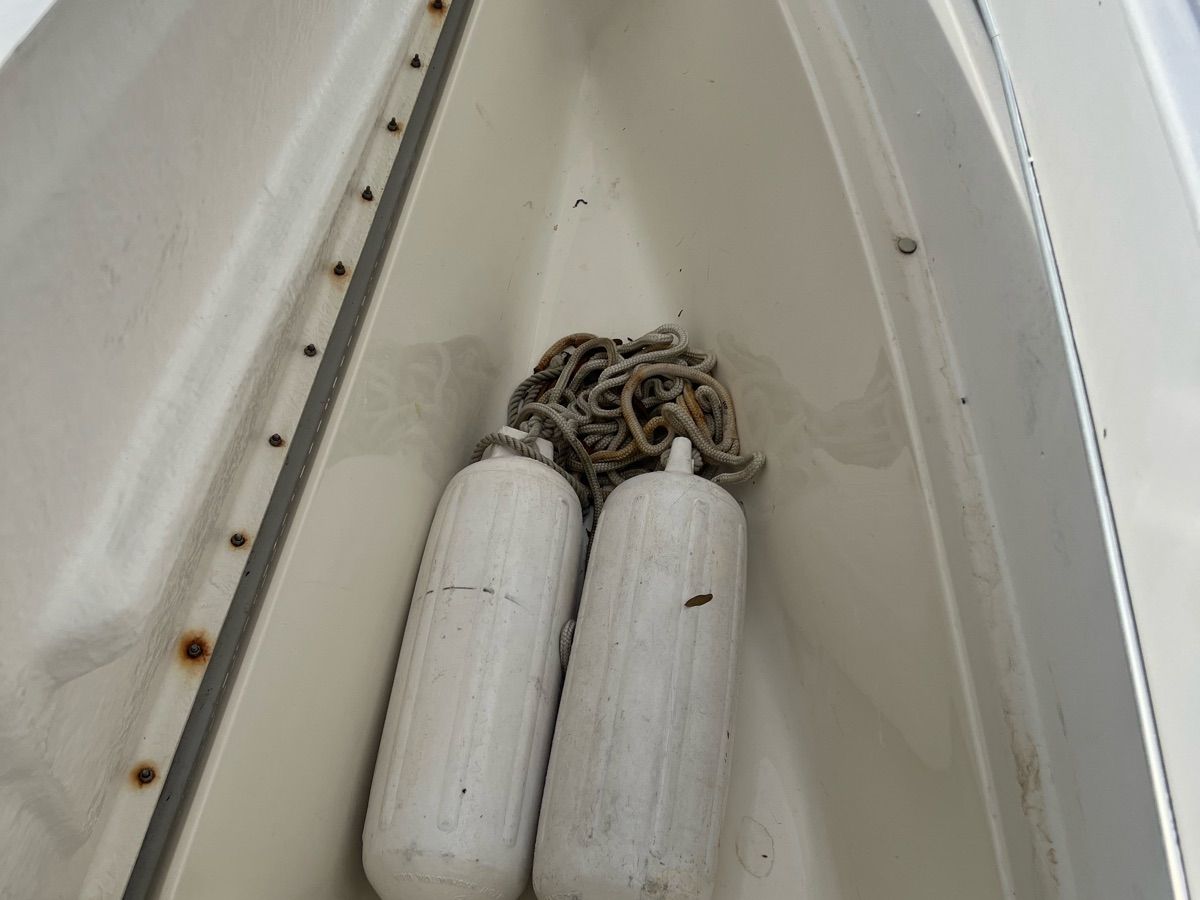 Two white fenders and a rope are in the bow of a boat.