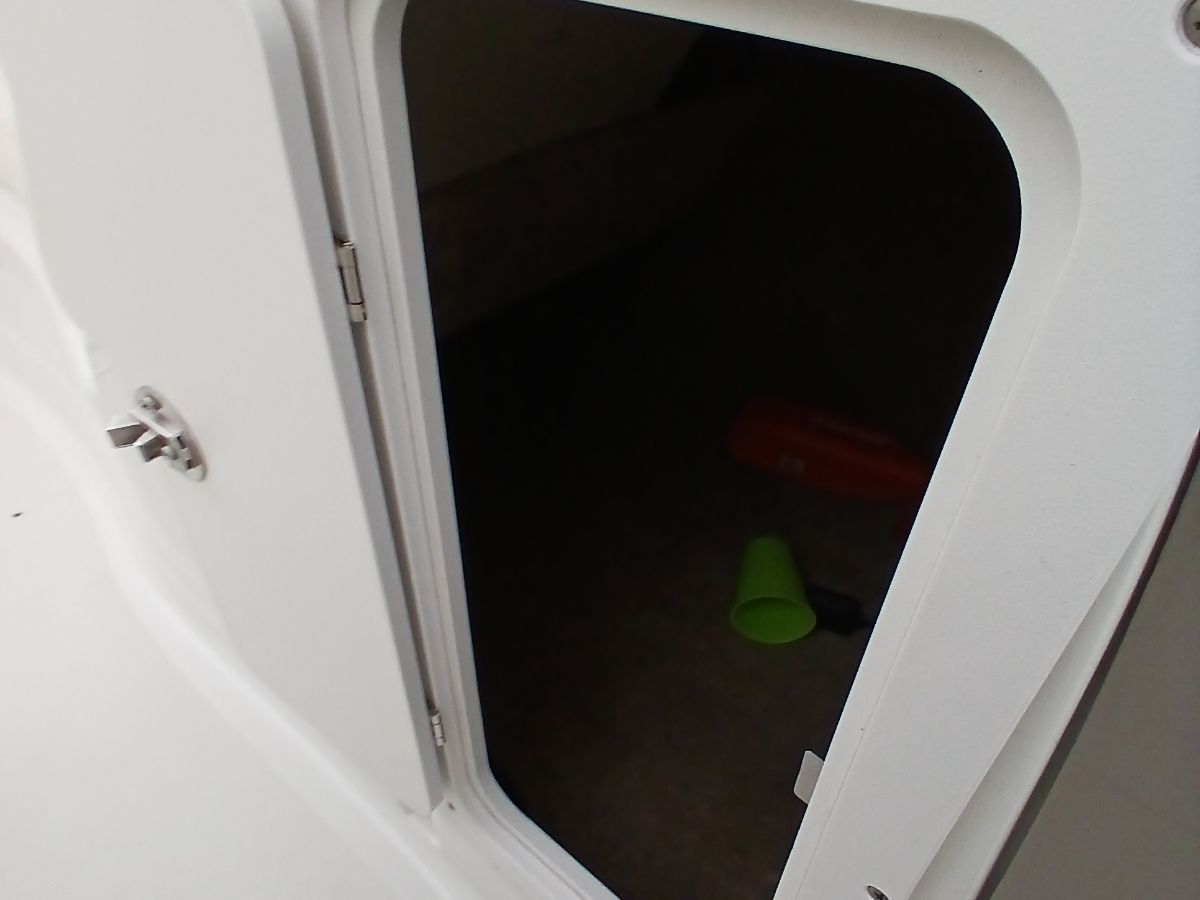 An open door on a boat reveals a dark interior with a green cup.