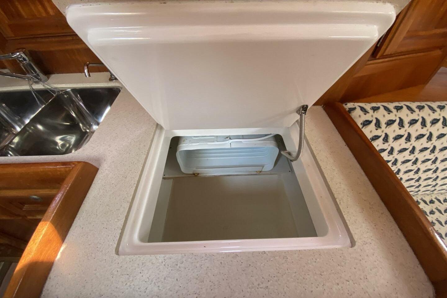 Open storage compartment in 1999 Dufour 39 CC yacht kitchen area.