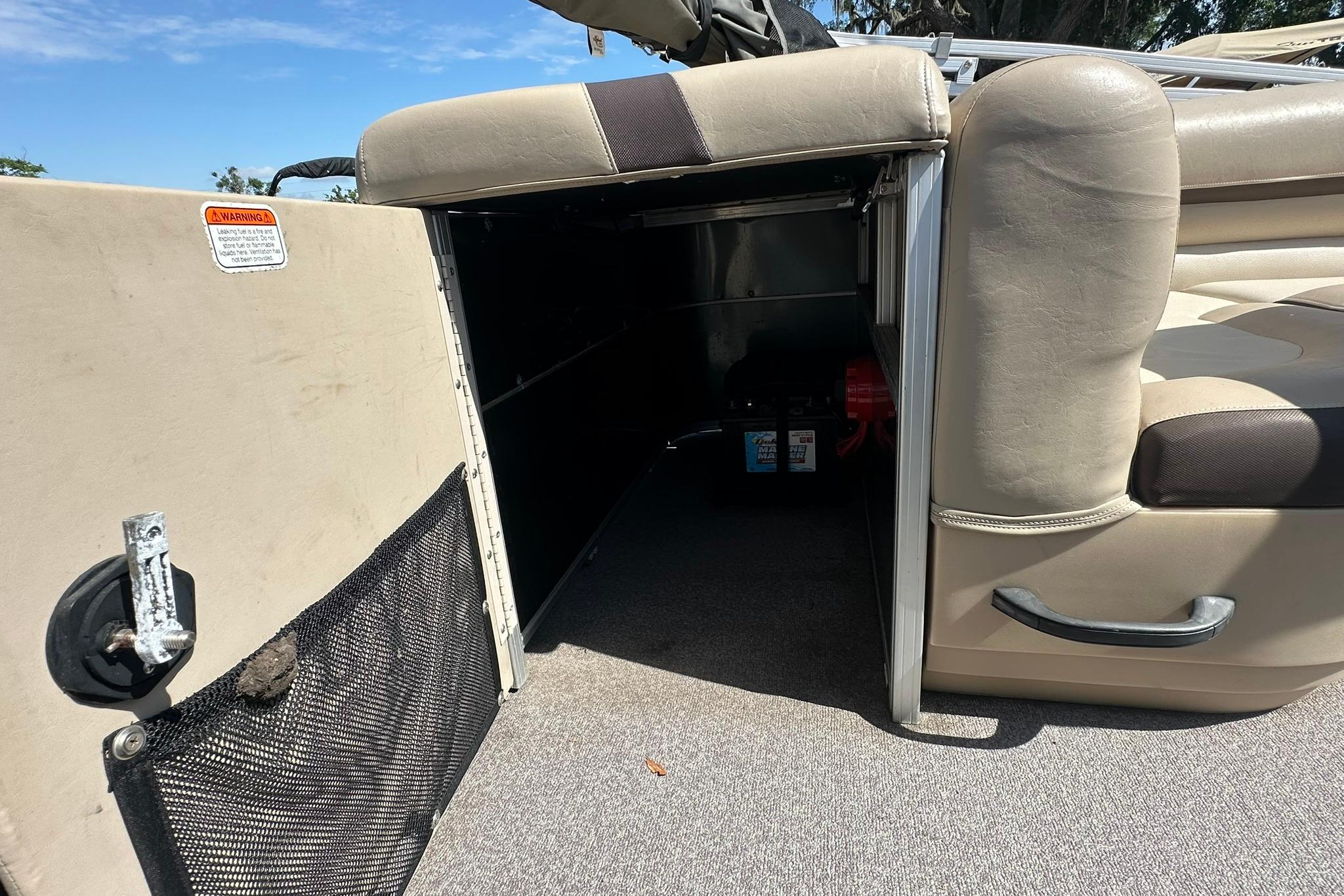 2016 SUNTRACKER Party Barge 20 interior storage compartment with seating and safety warning label.