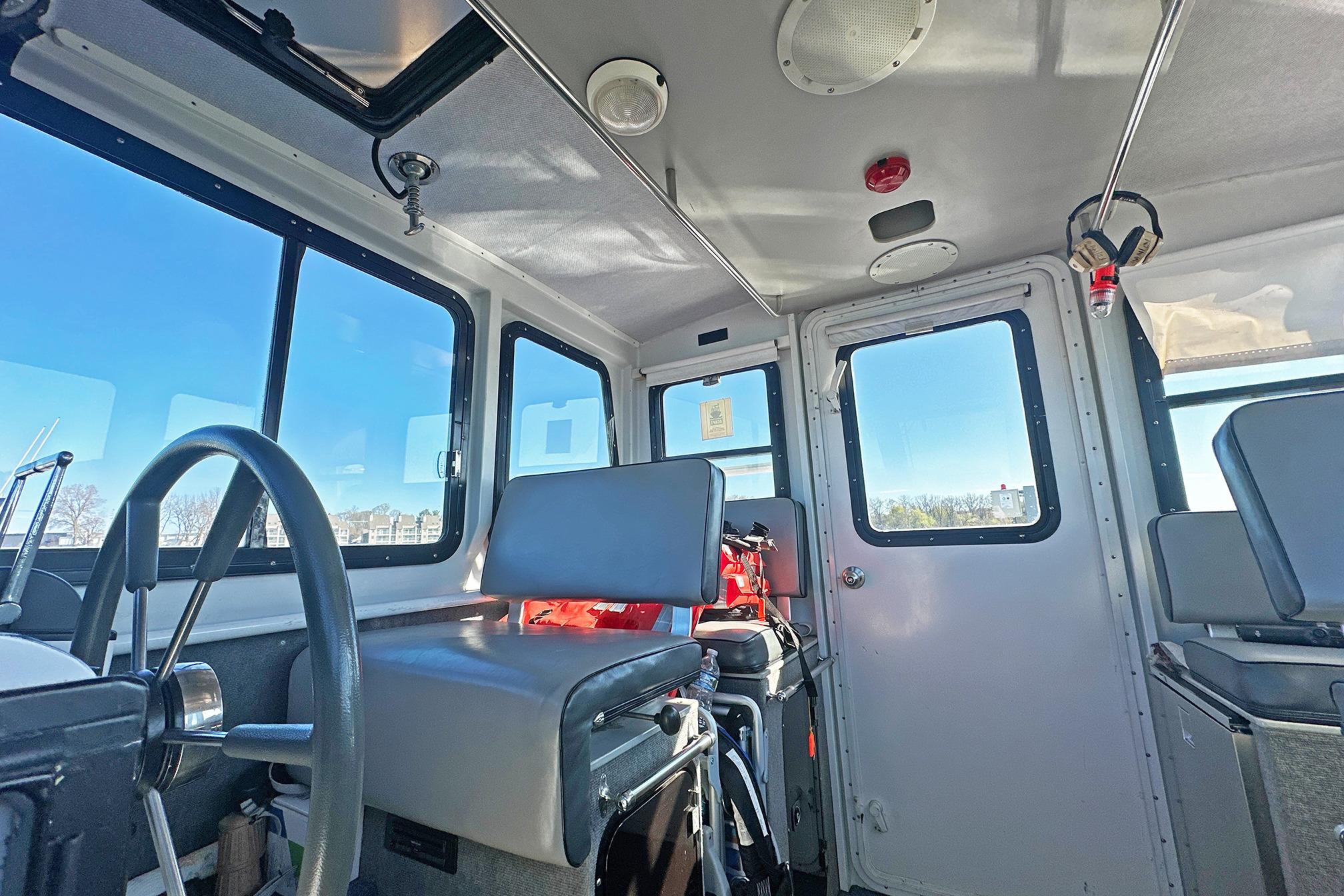 Interior of a 1990 Boston Whaler 36 Defiance boat, featuring steering wheel and seating.