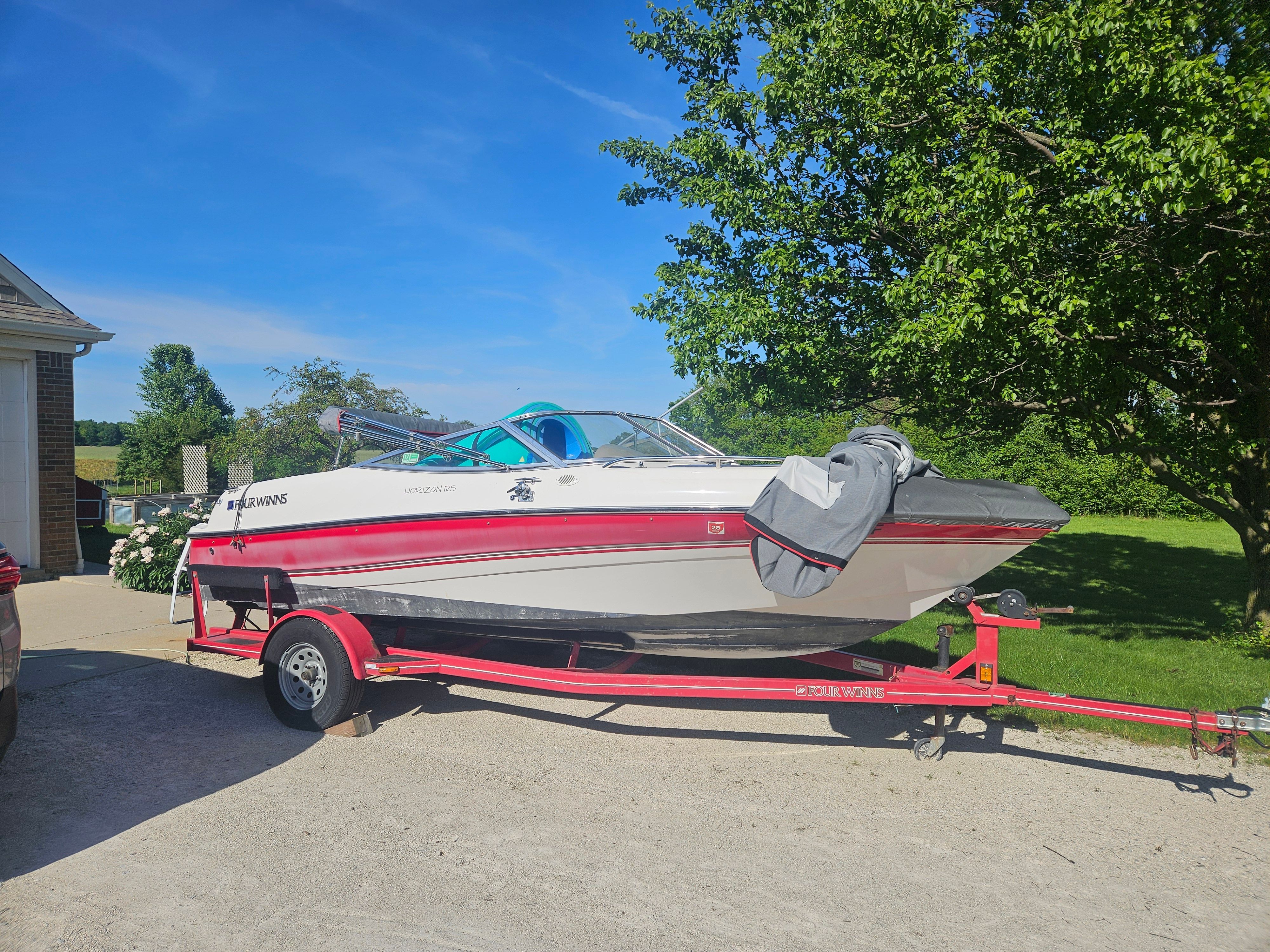 A white and red 1997 Four Winns Horizon boat on a trailer in a driveway.