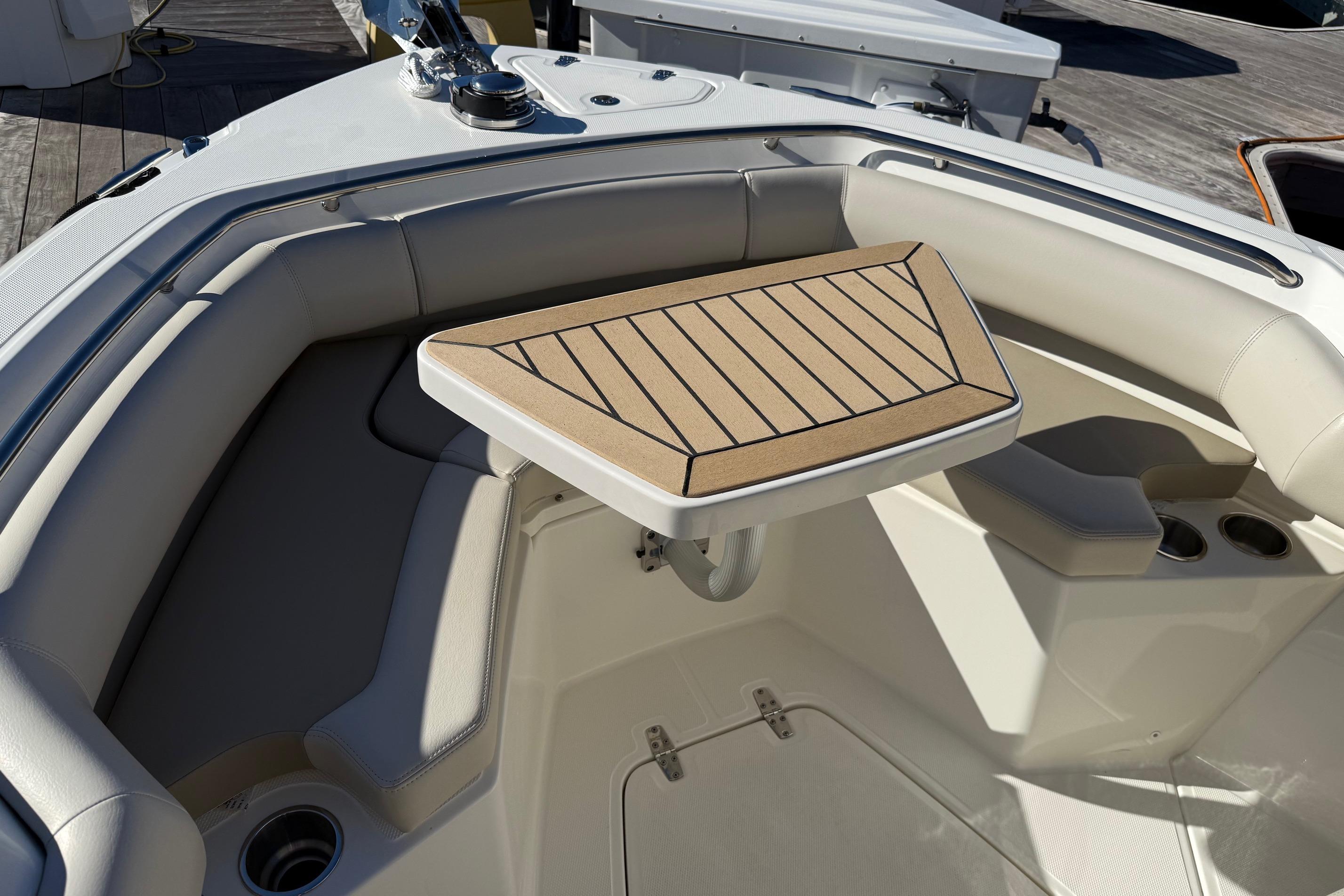 2025 Boston Whaler 250 Outrage boat interior with cushioned seating and a wooden table.