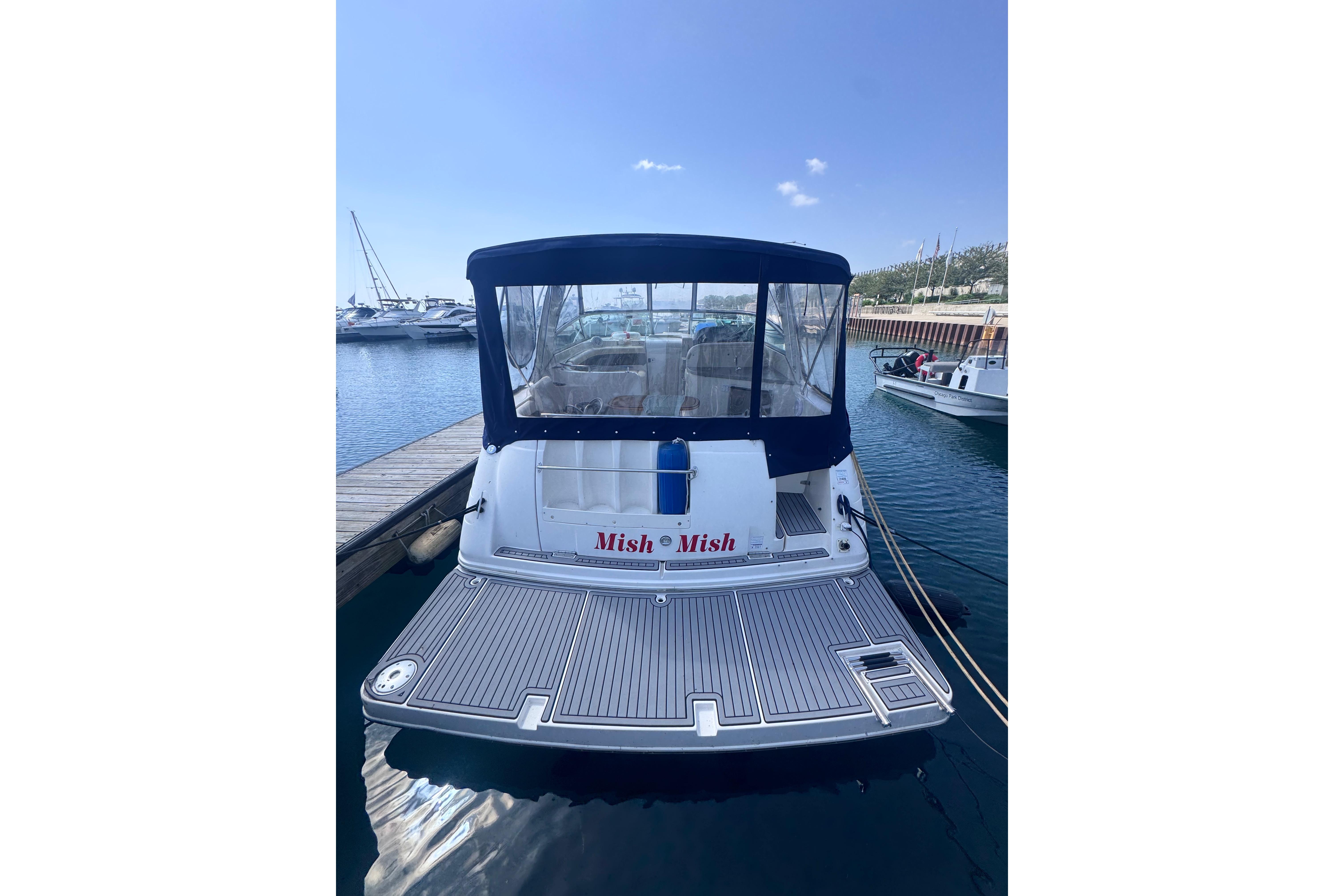 2003 Rinker Fiesta Vee 312 boat docked at marina, rear view with canopy.
