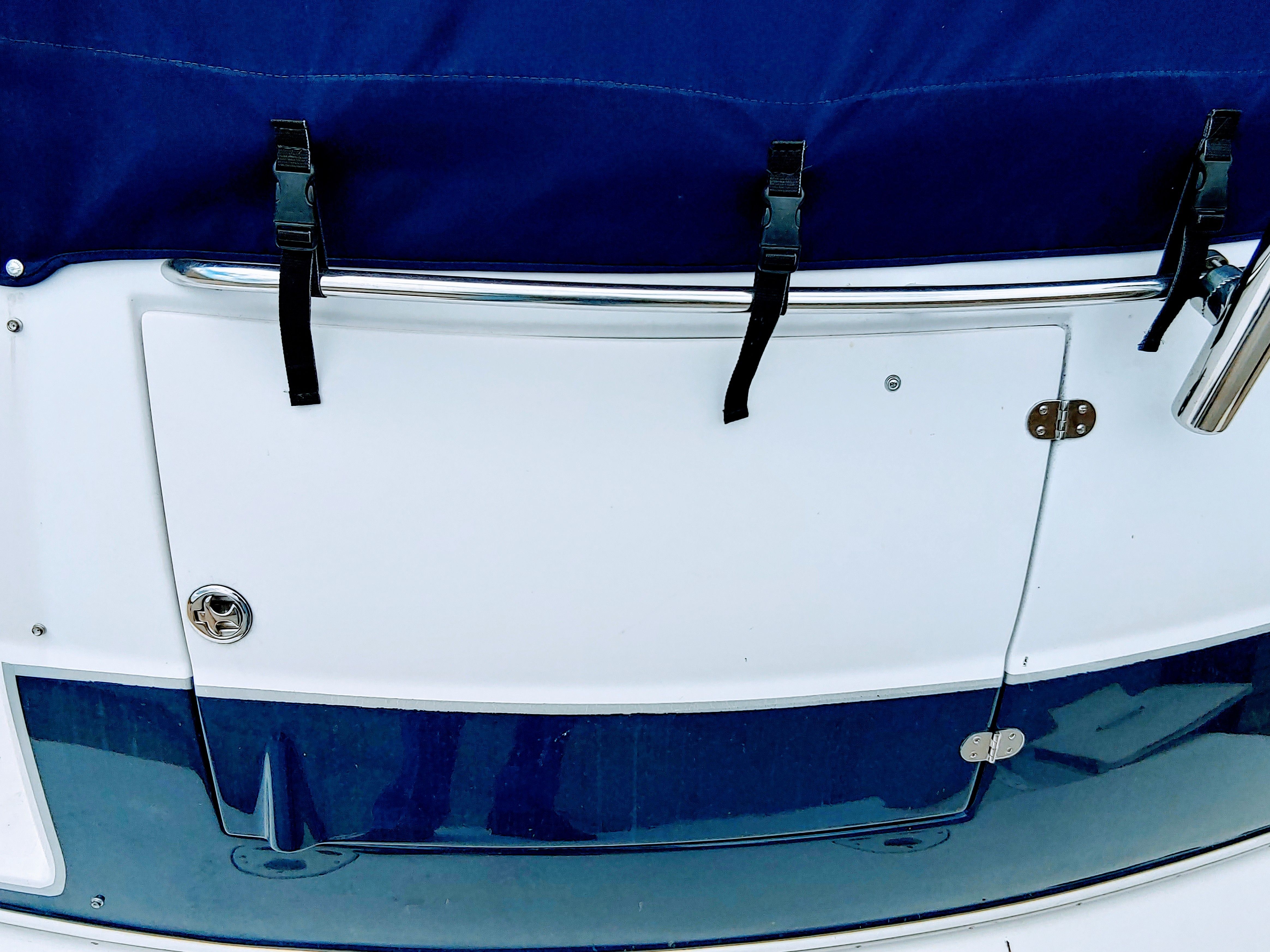 Close-up of a boat's stern with blue cover and metal fittings.