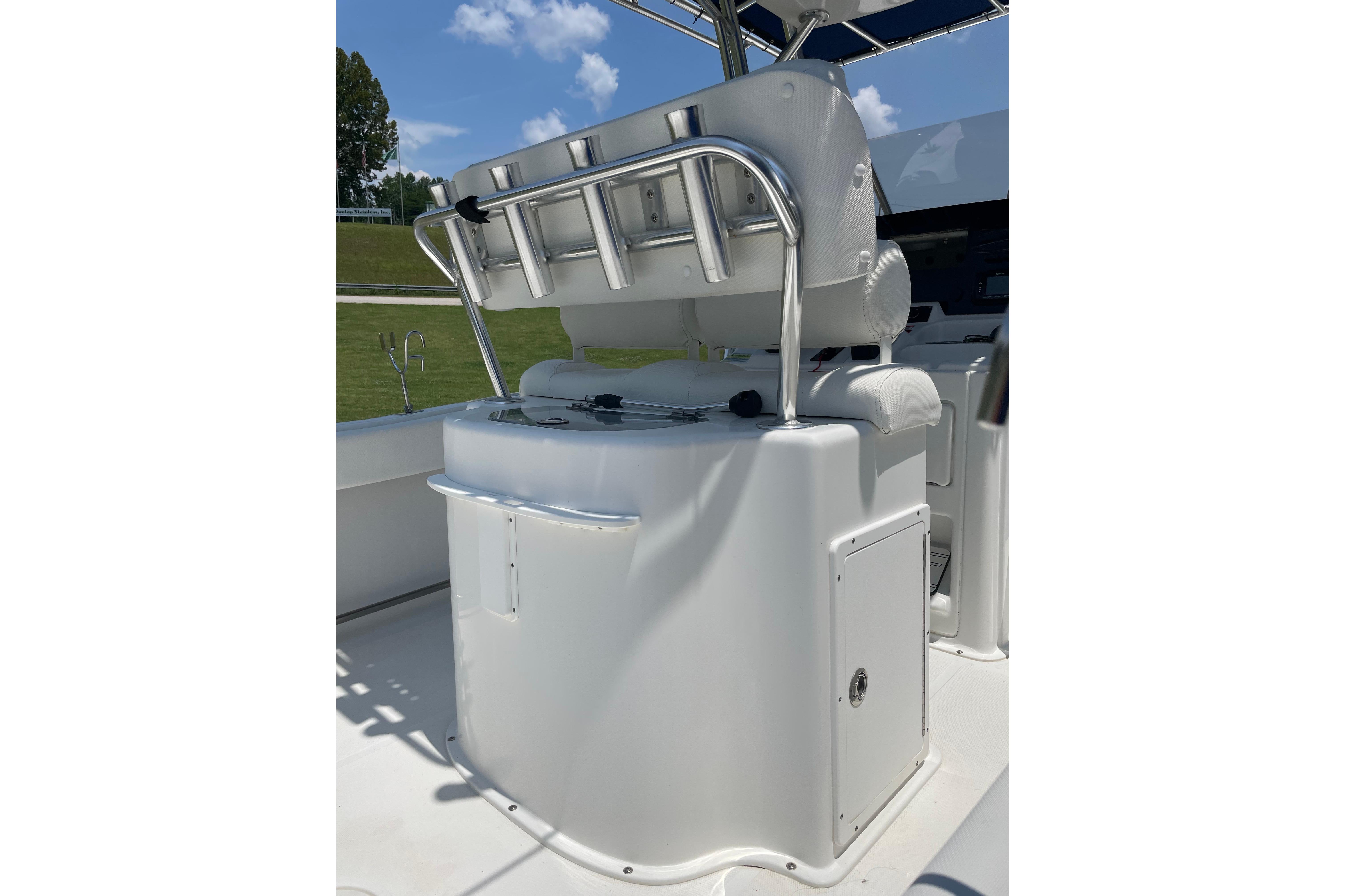 2018 Sea Hunt Ultra 234 boat console with rod holders and seating under a sunny sky.