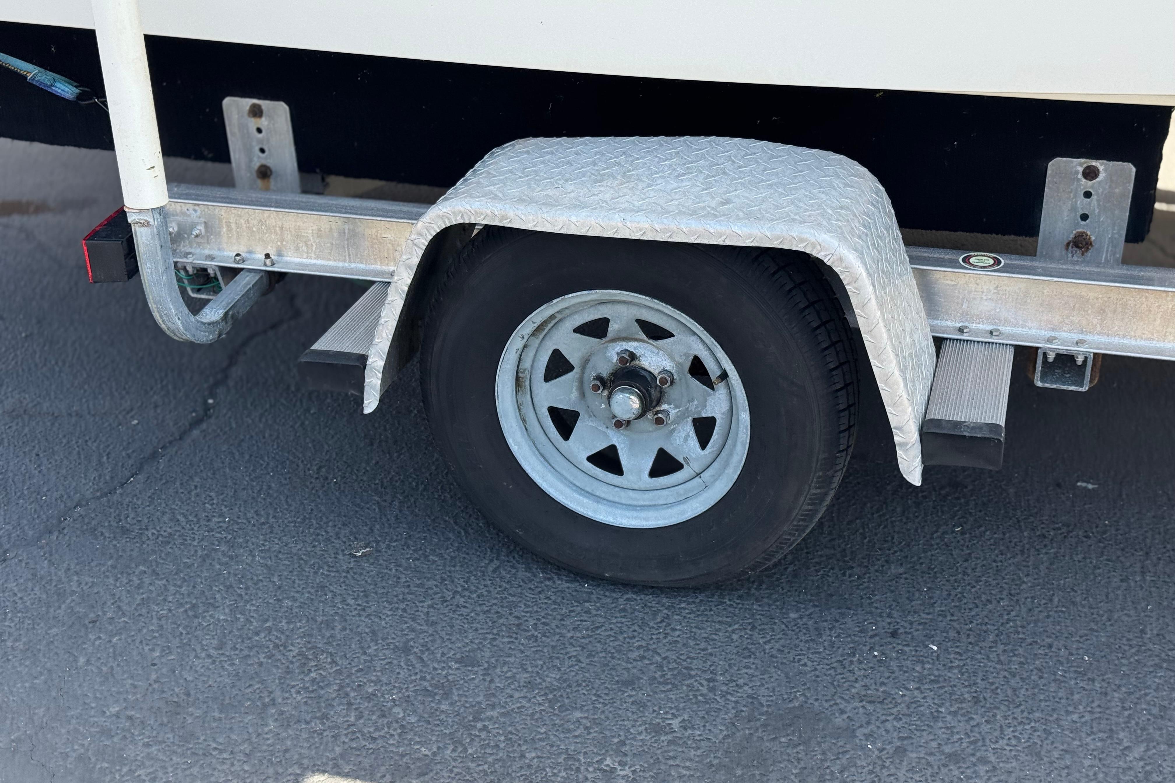 Trailer wheel of a 2006 Chaparral 190 SSi boat on pavement.