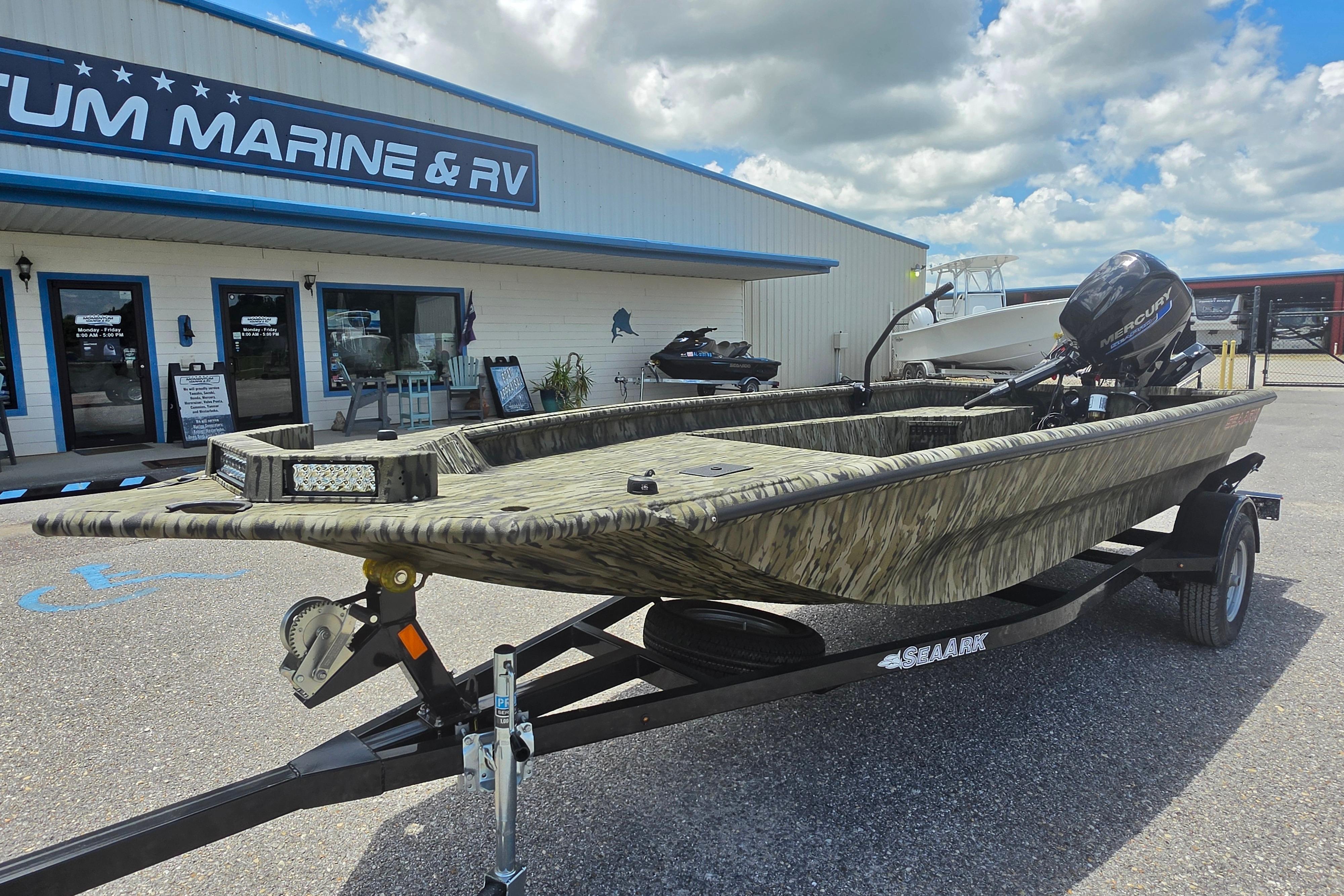 2025 SeaArk 1752 Slayer boat on trailer outside marine dealership under cloudy sky.