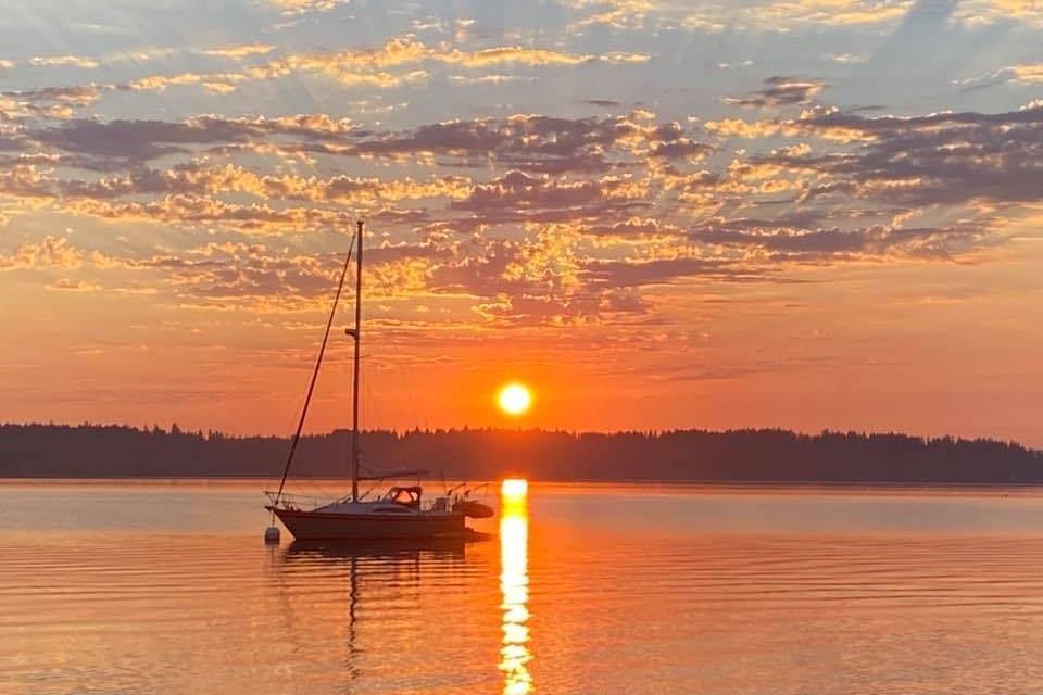 Sailboat at sunset on calm water.